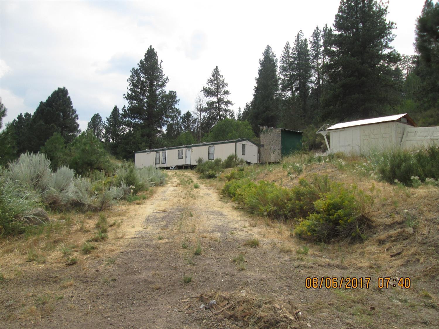 80 GPM well per 2002 well log and backs up to National Forest! This would be a perfect horse property with flat, usable land for pasture and a nice home site at the back of the property where the forest begins. MFG home needs repair and may not be salvageable, however, it could be good enough to fix up and live in while building your new home. No septic approval but tank and leach lines are in. Electric meter has never been installed. Owner is still removing some debris from property. Please note that the driveway is on the neighbors property. Said neighbor may be willing to negotiate and easement with a buyer.