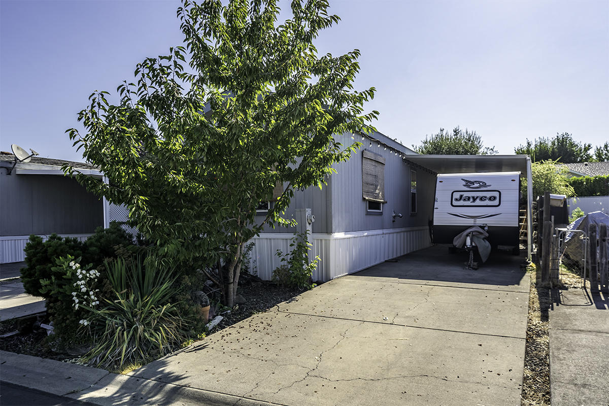 Welcome to this updated 2 bedroom, 1 bath MFH built in 2013 and located in a Family Park. The park rent is $377.00 which includes the water, sewer and trash. This lot has plenty of parking, including RV parking up to 25FT RV. with sewer hook ups. Two storage sheds, one is a workshop with power and workbench, the other shed is a garden shed. The backyard is fenced and private, decking, pond, 4 Hazelnut trees, 1 Cherry tree, and more. The home has pellet stove, laminate flooring, oak kitchen cabinets, range/oven, microwave, dishwasher, ceiling fans, come view this home located in Desert Mobile Estates.