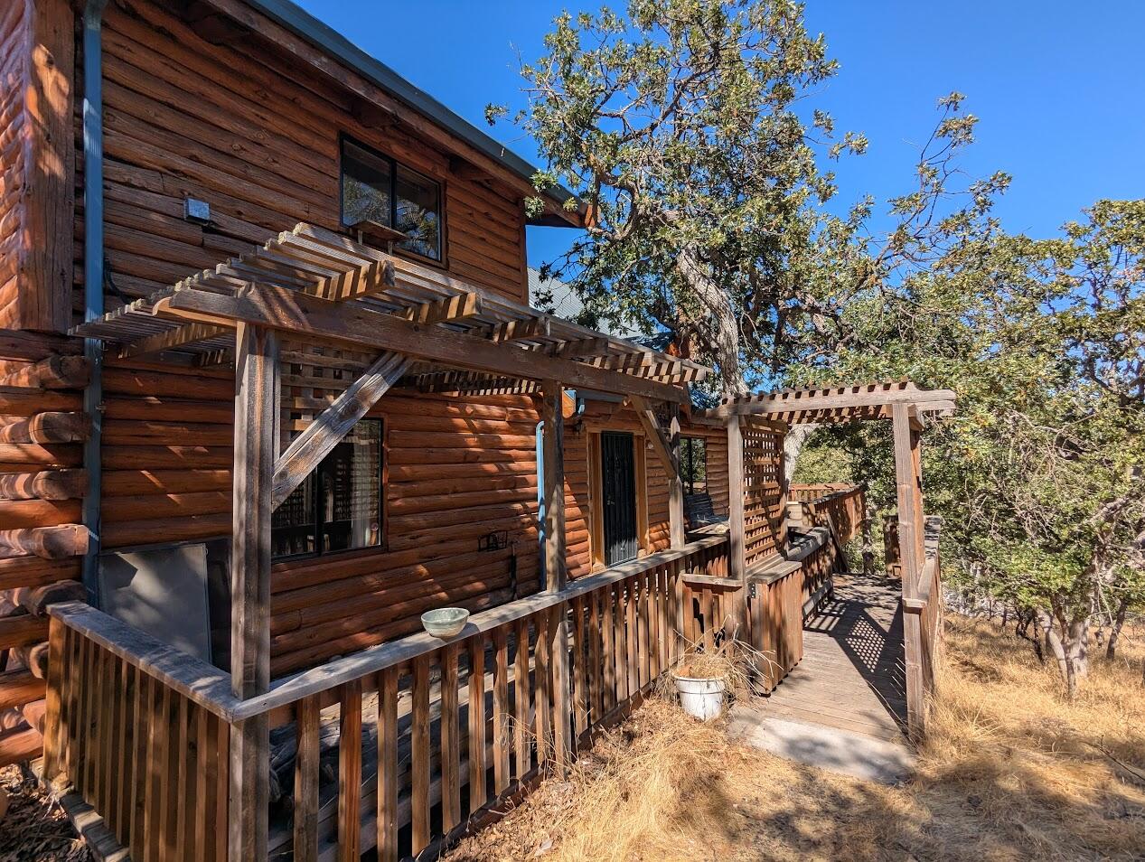 Charming, well-built log cabin with stunning mountain and valley views.  Tucked up a shared driveway, it offers peaceful privacy yet is minutes from town with quick freeway access-all paved to your driveway.  The open floor plan boasts soaring ceilings, a metal roof, and an office nook overlooking the vistas.  Enjoy a reinforced raised deck, perfect for a hot tub.  The daylight basement provides abundant storage and workshop space.  Upstairs, the ensuite primary retreat captures the views, while two bedrooms and a full guest bath with laundry are conveniently located downstairs.  Some updates are needed, including replacing flooring-making this a great project for someone looking to build sweat equity.