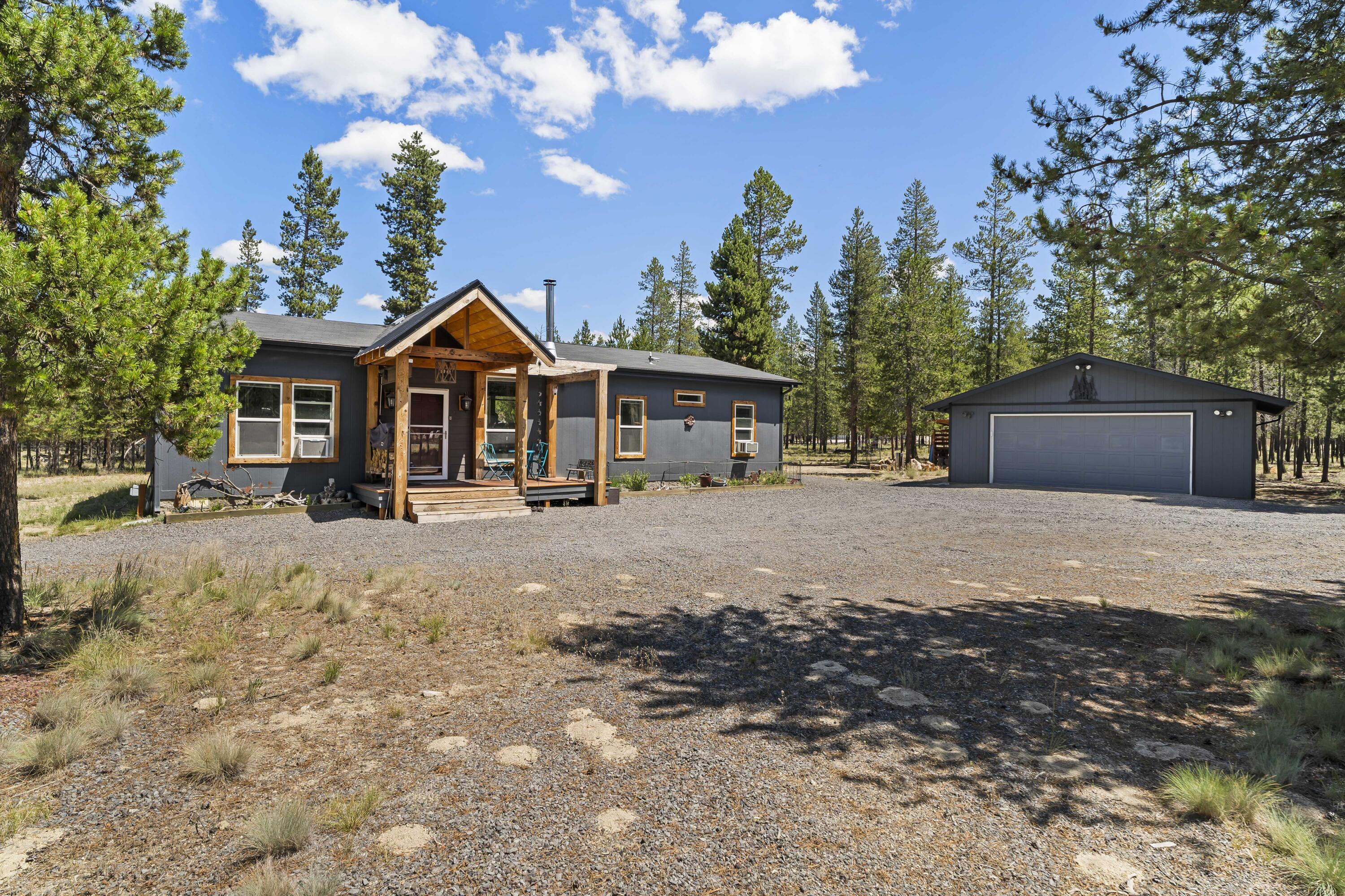 Embrace tranquility in Sun Forest Estates. Enter the gated driveway, step onto the new front porch and into your private retreat, a modern 2015 manufactured home that blends comfort and charm on a spacious lot. Enjoy open-concept living with warm laminate floors, a cozy wood stove, and a versatile family room. The kitchen features a stainless farm sink, ample cabinetry, and sleek concrete counters. The serene primary suite includes a sliding barn door, ceiling fan, generous closet, and private bath with soaking tub. Outside, find a detached two-car garage with wall heater, a separate shed, a solar greenhouse for year-round gardening and an RV hookup. Located minutes from La Pine's amenities and outdoor recreation, with low Klamath County taxes and an optional adjacent .98-acre lot to make this 2.25 acres. Don't wait to make this sanctuary yours.