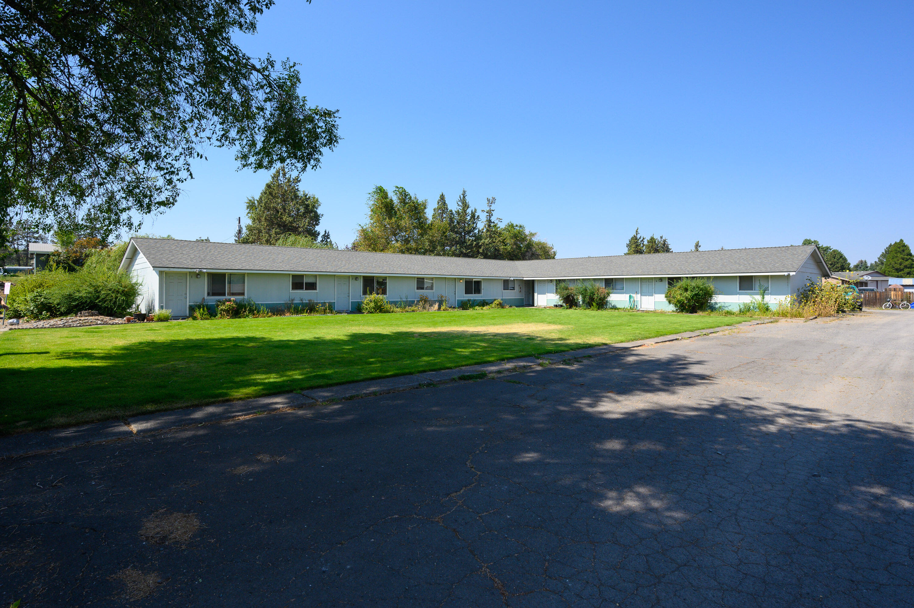 Nicer than new & highly upgraded 6-unit apartment complex w/all units on one level, brand new electrical panels and level 2 EV charging for each unit, 3 parking spots per unit, a coin-op laundromat, & a large yard w/mature & safely located/shaped trees all maintained via sprinkler system. The roof is newer & recently had upgraded ventilation added. The exterior paint was recently redone. Several of the units have new LVP flooring & all are in very good condition. Five of the units are 784sf w/2 beds & 1 bath & all have an identical layout. The kitchens are generous & have exterior vented range hoods. Bathrooms all have a tub/shower combo & are well ventilated. The layout is open & the one-bedroom unit is identical to the others but is missing the front bedroom. The onsite laundromat fills that corner & has coin op units that are in great shape. Quick access to Bend & all of Redmond through unclogged roadways & existing/upcoming trails make this apartment tough to beat!