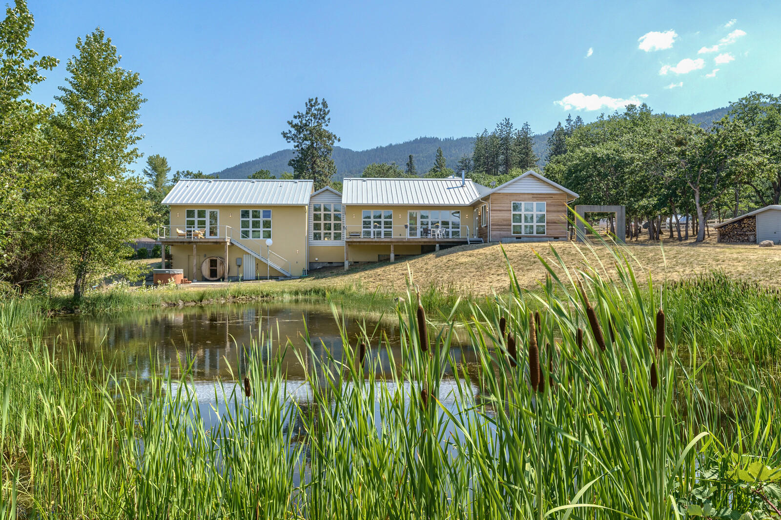 Amazing modern farmhouse on over 5 acres with views of Emigrant Lake. This single level Earth Advantage home with solar hot water has an open floor plan, vaulted ceilings and is filled with natural light. The living area has an energy efficient fireplace that can heat most of the house. The kitchen has custom cabinetry, a walk-in pantry and high end appliances. There are two wings off the great room, providing privacy. The primary suite wing has two full baths with custom tile work, one with a soaking tub with beautiful lake and mountain views. There are two walk-in closets and a nearby laundry room. The guest wing has two bedrooms with a jack & jill bathroom, a separate w/d and entrance. A barn with a shop, parking and storage has a guest apt. with a full bath, kitchen and living room. This unique property has lovely landscaping, a hot tub and sauna. It's just minutes to Ashland and at the edge of Southern Oregon's bountiful nature. Truly a don't miss opportunity.