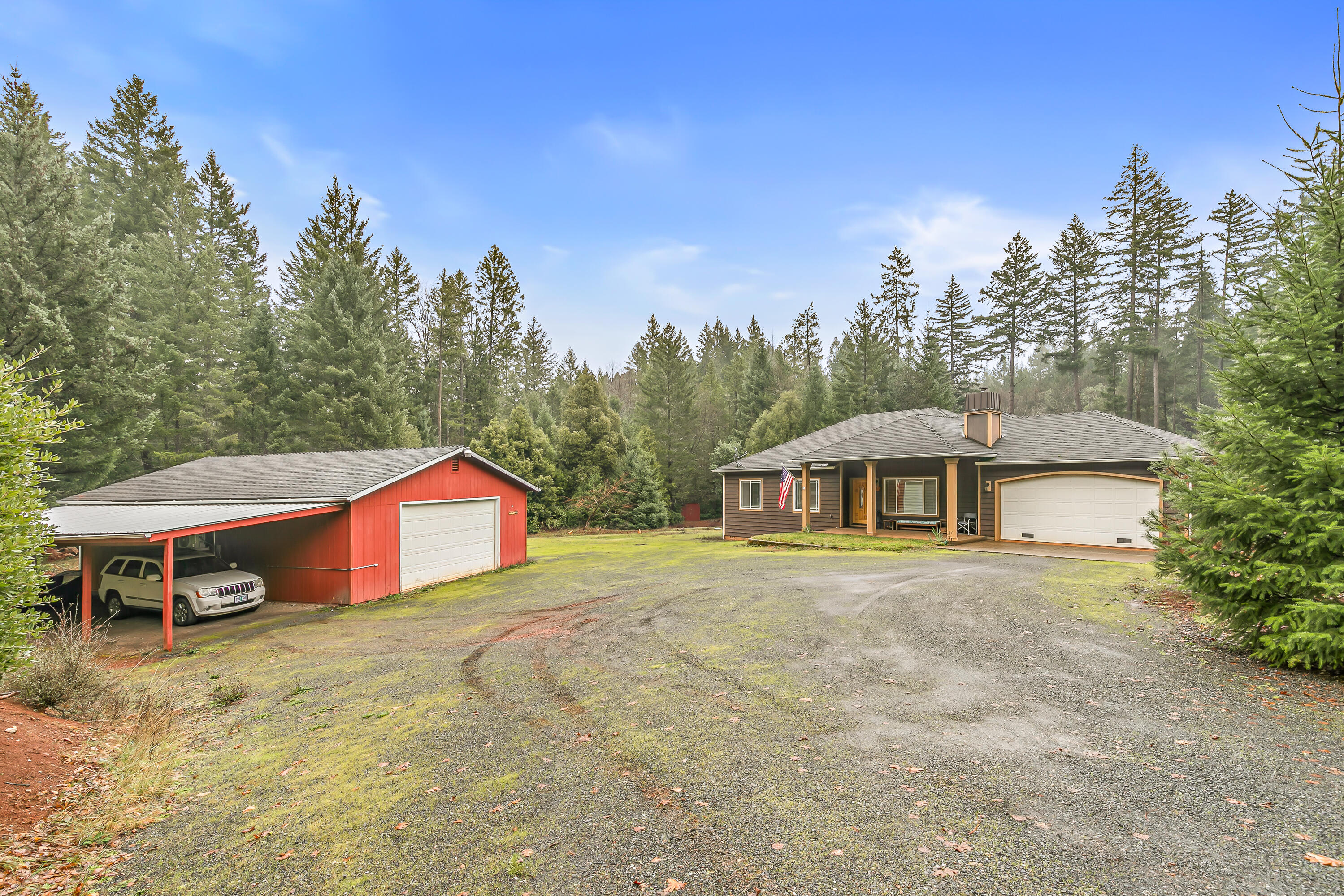 Assumable 2.25% interest rate!! If you're looking for privacy on acreage mins away from downtown Cave Junction, this is the one for you! This charming 2003 built home features 3 bedrooms, 2 bathrooms, 1540 sq ft, 5+ usable & fenced acres, open floor plan, walk-in pantry, high ceilings, central vacuum system, woodburning fireplace, attached 2 car garage, detached finished 1120 sq ft shop w/ mini split system & attached carport, additional detached storage shed, partial RV hook ups (water & septic), spacious covered deck, gated entryway, & much more! Primary suite is spacious w/ coffered ceilings, walk-in closet, walk-in shower, and access to the covered deck.  Transferable home warranty included with the sale. Perfect opportunity for anyone looking for a low maintenance home on a large lot! This one won't last long on the market, so contact your agent today for a personal tour, before it's too late!