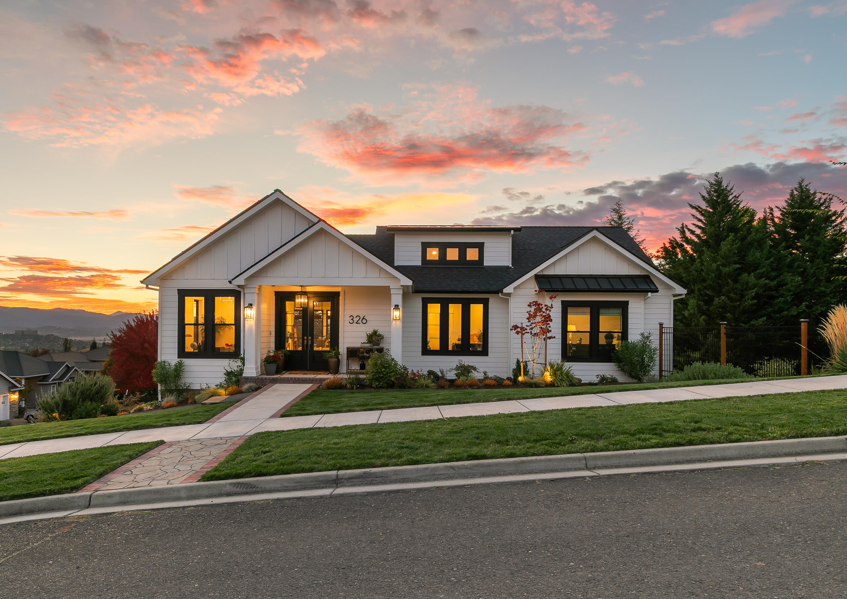 Perched above the valley in desirable East Medford, this stunning home showcases modern design, tasteful finishes & sweeping views. The open-concept layout features tall ceilings & expansive windows, creating a bright & welcoming atmosphere. The spacious great room connects to the kitchen & dining area, highlighted by quartz countertops, a butler's pantry & access to a large composite deck for enjoying the views. The primary suite is conveniently located on the main level, with a spa-like bathroom featuring a tiled shower, large soaking tub & walk-in closet. A 2nd bedroom & dedicated office space are also conveniently located on the main level. Downstairs, 2 additional bedrooms and a second living area with a built-in wet bar offer flexibility for everyone. Thoughtful touches continue with solar panels, an EV charger in the oversized two-car garage & well-established landscaping. Modern sophistication meets timeless charm — the perfect blend of comfort, design, & breathtaking views.