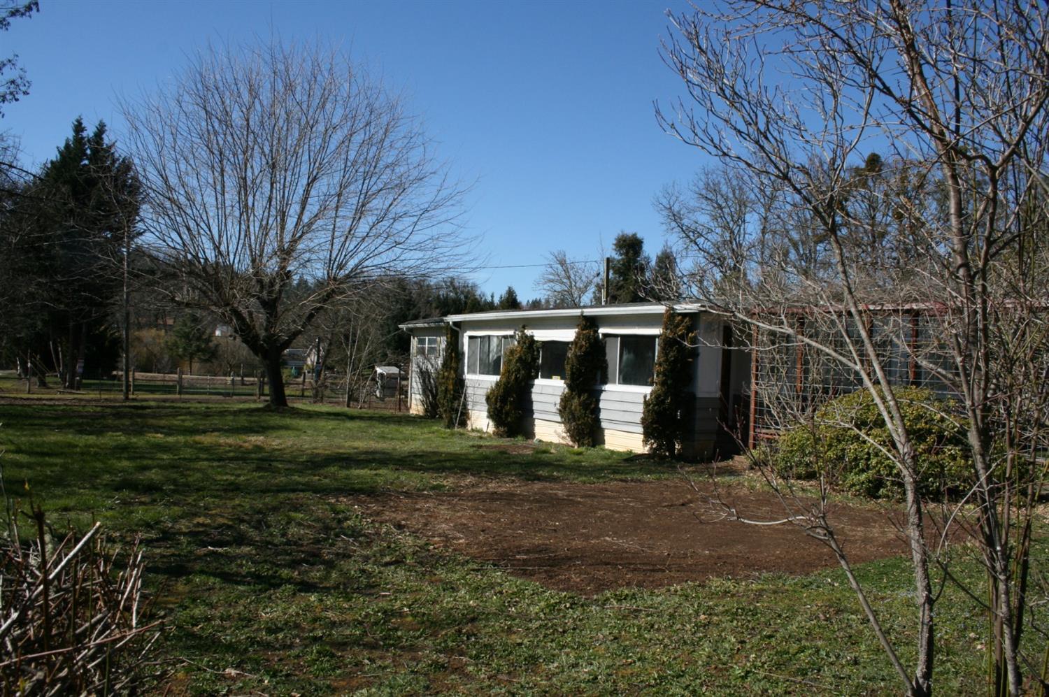 Nice 1.04 acre property consisting of 2 tax lots (each .52/ac), in a quiet neighborhood. The home is a 1971 doublewide manufactured home, 3 bedrooms 2 full baths, 1710 sq ft., is clean and cozy. In addition, there is a 1963 singlewide, being used as storage and condition is unknown. Exterior features include, gated entry, carport, fruit trees, raised garden beds and a seasonal creek at the back of the property. Remove a few trees and one could open up some lovely mountain views. Buyer will want to perform due diligence regarding uses of the 2 lots as well as condition of property and improvements.