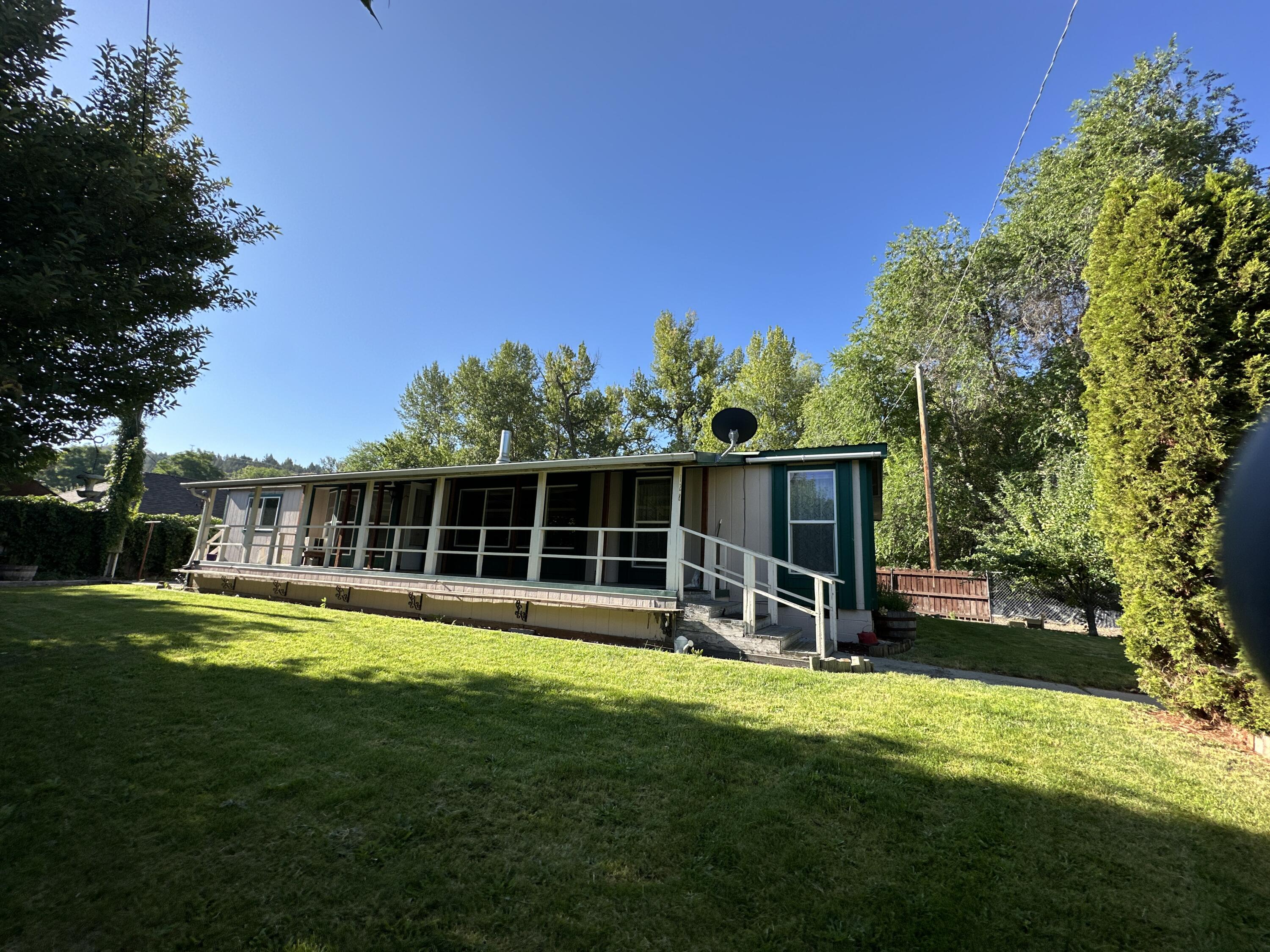 Enjoy the sound of Canyon Creek as you sit on your large covered deck. Nice fenced yard, landscaped, shallow well for watering, lots of privacy with all the foliage. Home offers 3 bedrooms, 2 bathrooms, mud room, family room & living room, attached 2 car garage, carport, lean to. Large kitchen with island, lots of counterspace and tons of cabinets. Primary Bedroom has walk in closet and primary bathroom. Home has 3 heat sources, Blazeking woodstove, oil monitor heater and electric furnace. Located within minutes of downtown John Day. Home requires flood insurance.