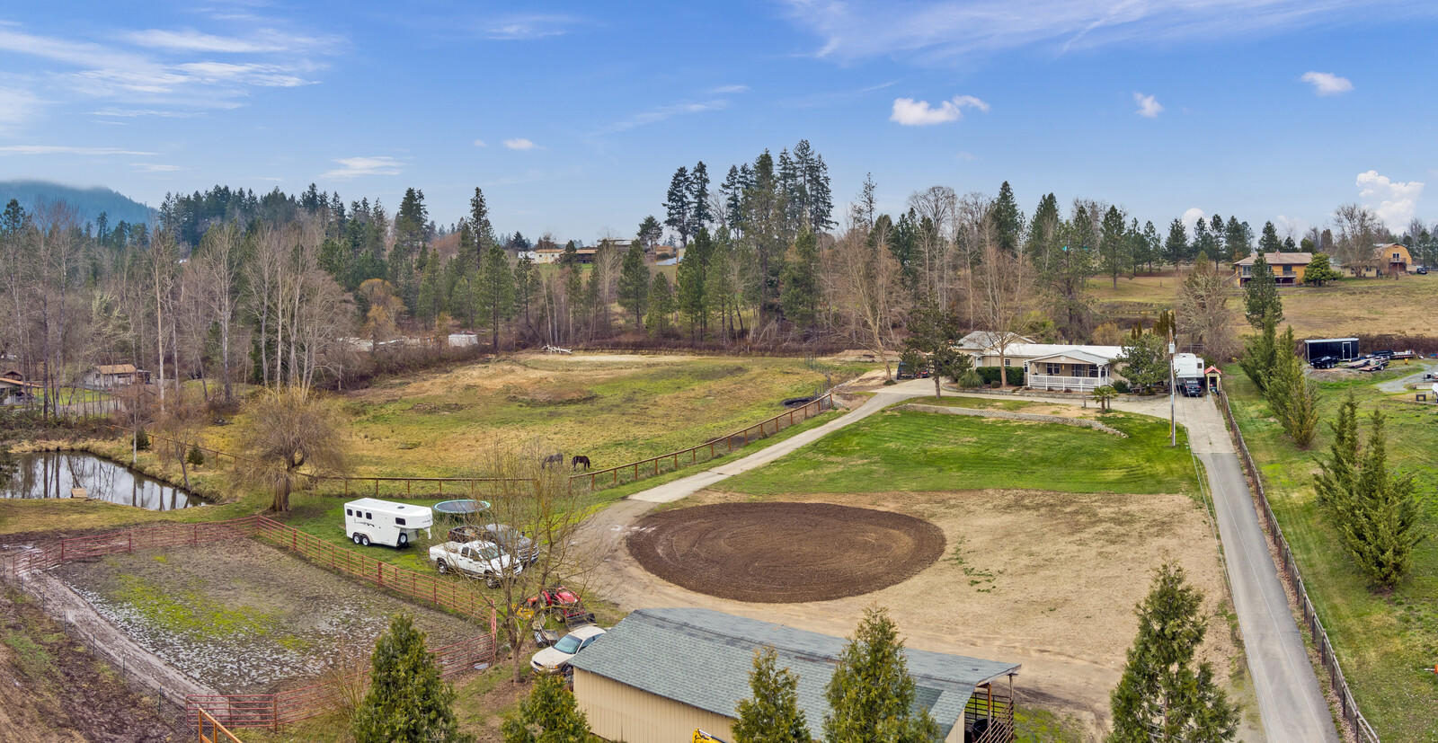 Peaceful 3.38 acres with irrigation and plenty of room for hobbies and toys!  Perfect for 4-H projects, complete with shed row stalls currently used for horses.  The circular drive makes for easy maneuvering on this gently rolling property.  There is lots of flat space, a large pond, attached 2-car garage and RV hook-up.  This spacious 2,002 sqft home is manufactured with stick built addition and features granite counter tops, a large living area, 4 bedrooms, plus an office, 3 full baths (master has dual sinks, jetted tub and shower).  There is a laundry room, plus a separate utility room, 2 heat pumps, a roomy deck and the 1-year new hot tub is included!  Enjoy the lovely views of your property from the covered front porch.  The ultimate gift: Privacy!