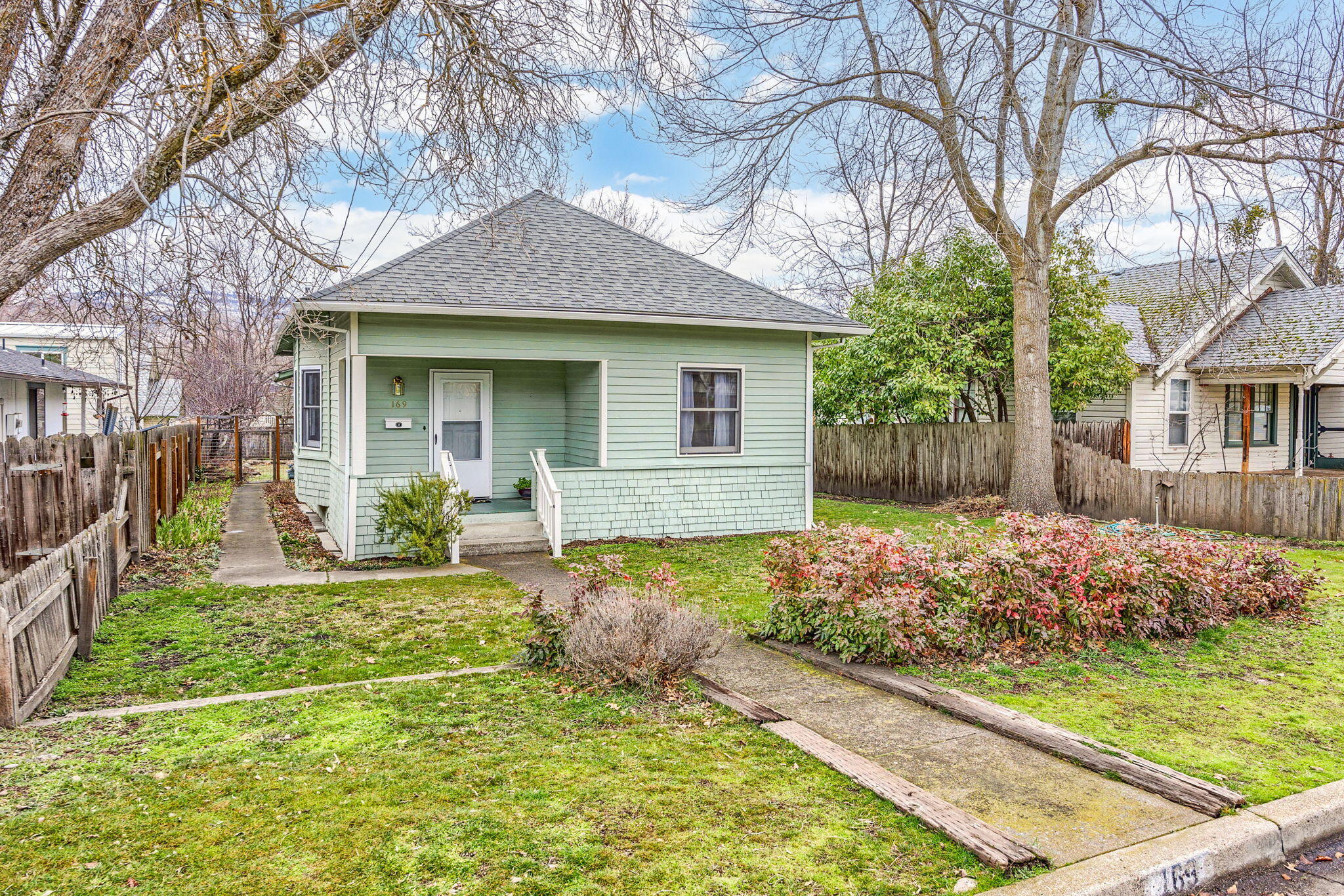 Charming cottage on a wonderful lot with alley access and just blocks to downtown Ashland. A lovely front porch with views and mature trees greet visitors and provides a welcoming scene. Inside is a well-cared for home boasting 3 bedrooms and 2 full bathrooms. The living room has built-ins and high ceilings that add to the period charm. A front bedroom overlooks the front yard and could easily serve as a home office or media room. The eating area has a bank of windows and is filled with natural light. A passthrough to the efficient kitchen is a sweet touch. Two bedrooms sit at the back of the home with two full bathrooms, one in the primary suite. A mud/laundry room opens to a back deck that overlooks the lovely backyard that has many mature plantings and fruit trees. The level lot would be perfect for garden beds or play space. With alley access, the potential for an ADU is simplified and would add great value/flexibility to this wonderful home. Truly a fantastic opportunity!