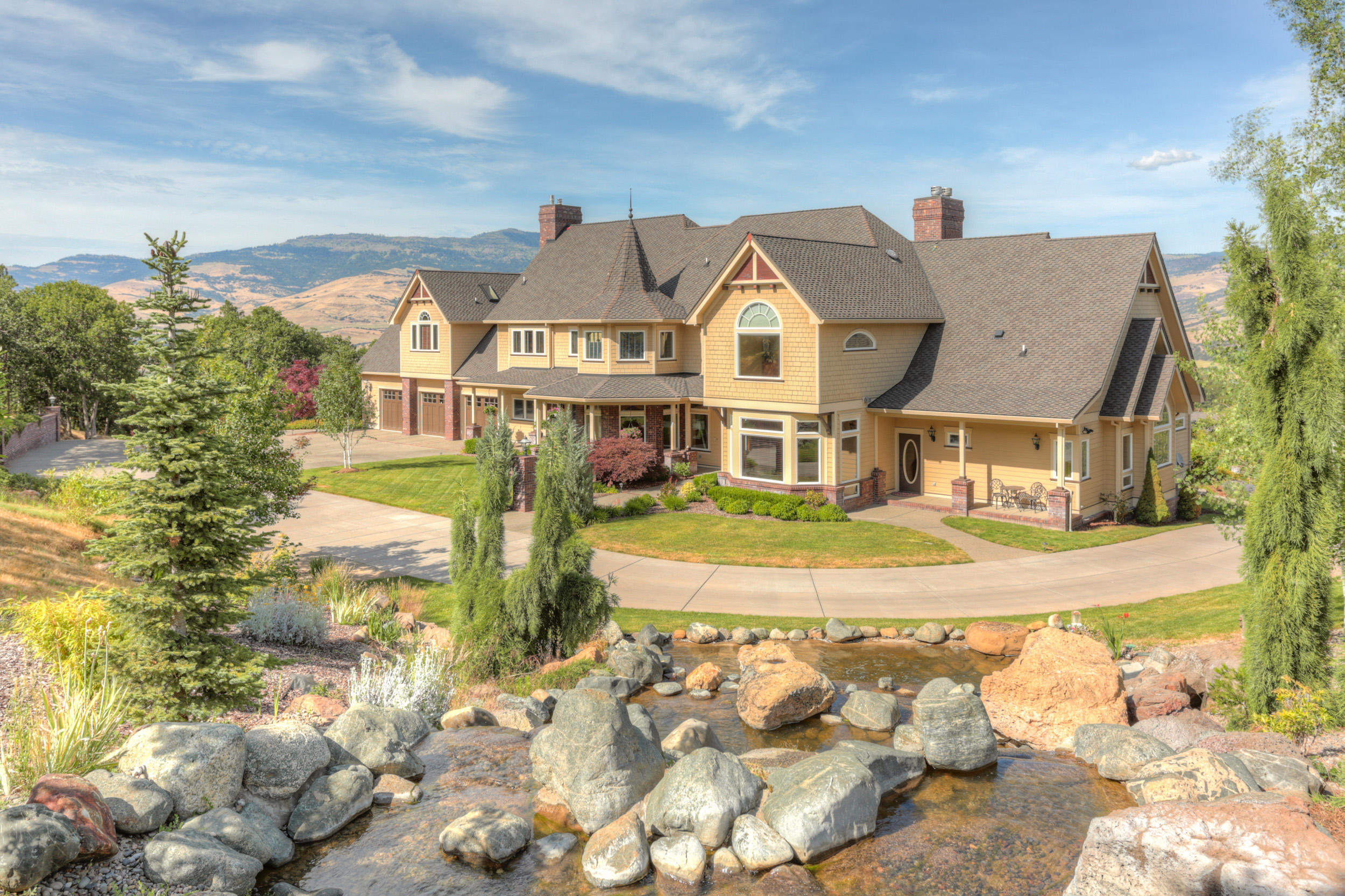 Serenity & Grace
This gorgeous home features breathtaking panoramic mountain views. The stunning 2-story design allows for easy main-level living while still providing an abundance of extra living space above.  Main level includes a luxurious bedroom suite w/fireplace, formal dining room, dramatic living room with floor to ceiling windows, a majestic fireplace, spacious gathering room, gourmet kitchen w/ center island, den w/ fireplace, 2 & 1/2 baths, full laundry room, an oversized 3-car garage w/half bath & extra storage space. Second level amenities include, 3 - bedrooms, 2-full baths & a fabulous great room. Partial basement w/ secure storage room & an equipment room. The exterior is surrounded by natural beauty, views, a captivating, cascading rock waterfall, pond, luscious 60' vanishing edge swimming pool, outdoor entertaining space & mature landscaping. A 1398 Sq. Ft. detached additional living space w/ garage complete this fabulous property!