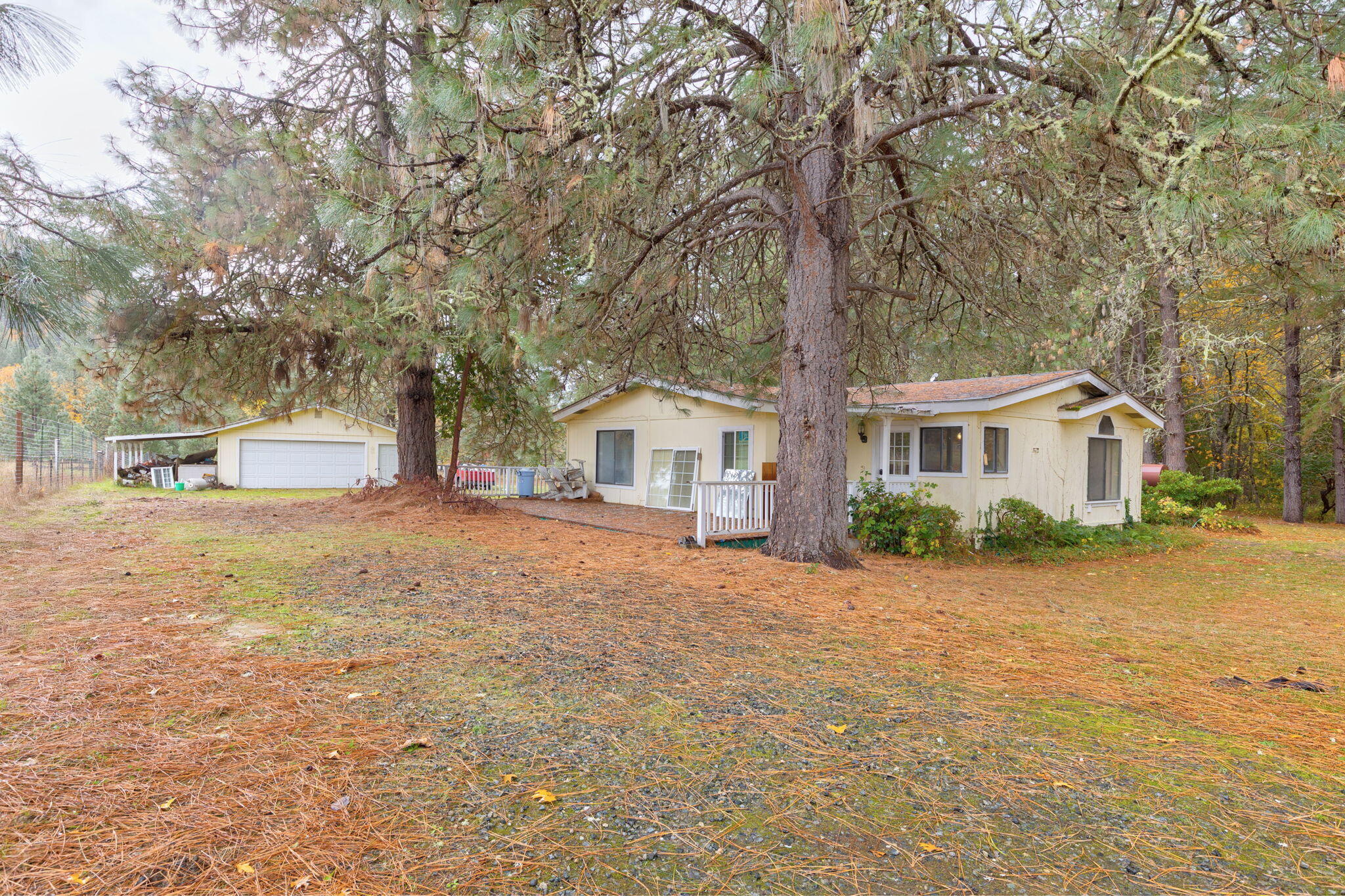Tucked back off the road, this peaceful 5-acre property offers level land and endless potential. The 3-bed, 2-bath, 1,776 sq ft 1990-built manufactured home is ready for someone to bring vision and care—finish the projects already started or remove the home and build your dream residence. Inside, you'll find wood flooring through most of the home, a mini-split system, newer oil heater, and a pellet stove for comfort. The living room features vaulted ceilings and an open floor plan, while the desirable split-bedroom layout provides privacy. The primary suite includes an en-suite bath and a walk-in closet accented with rustic barn-style doors. A detached two-car garage adds convenience and storage. A great opportunity to create something truly special on a beautiful fully fenced & gated piece of land.