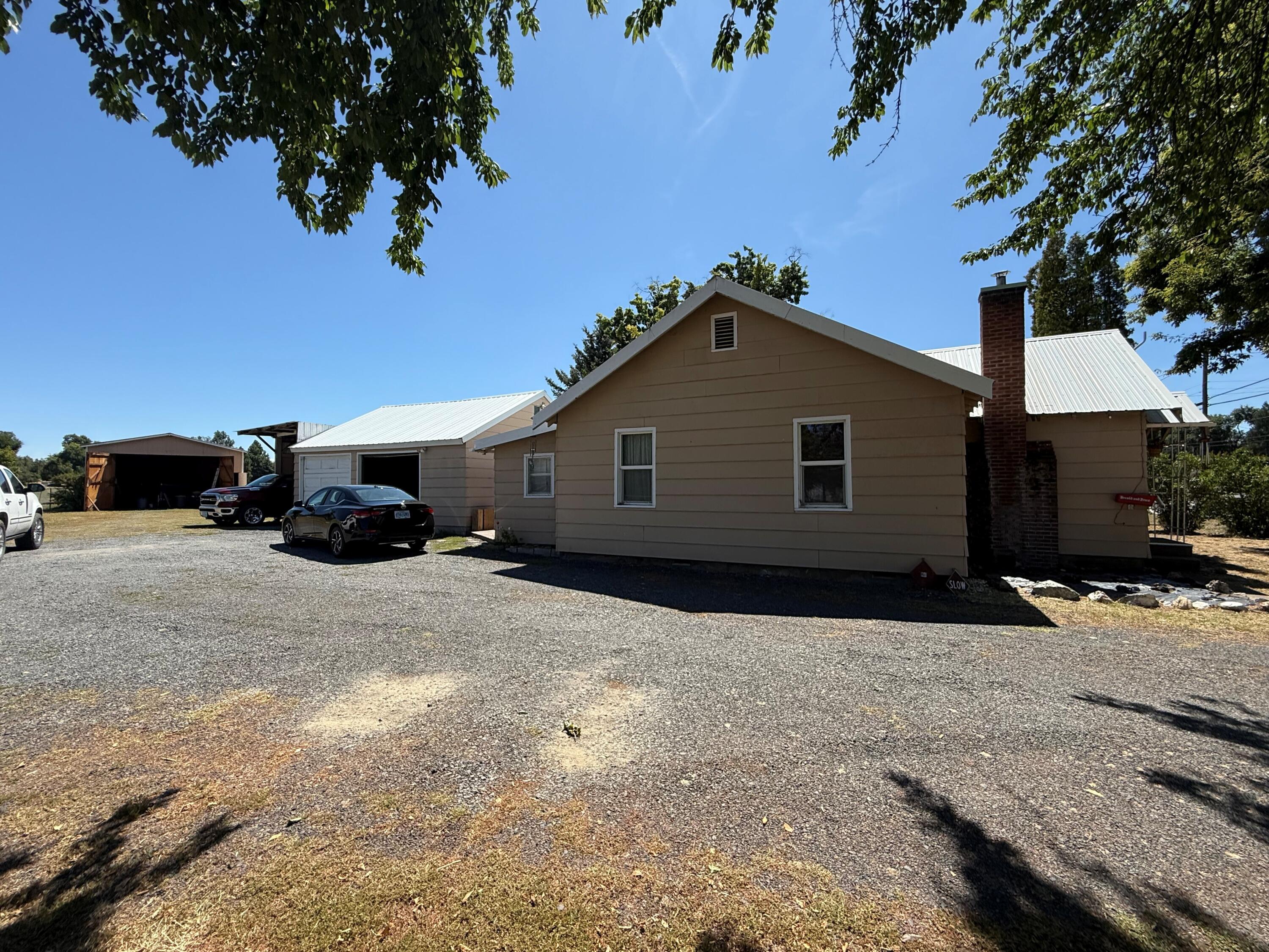 Endless possibilities! This property has so much to offer including over an acre of fenced, irrigated level land; 22'x30' shop with power, workshop, metal roof, area and a lean to off the back; detached 2 car garage with a metal roof and an attached 8'x20' carport for an RV, boat, etc.; storage shed. The home offers 3 bedrooms, 1 bath with Walkin shower, kitchen with an eating area, wood burning fireplace in living room, newer gas heating, original hardwood floors beneath the carpet, separate laundry room with large pantry, and has a metal roof.