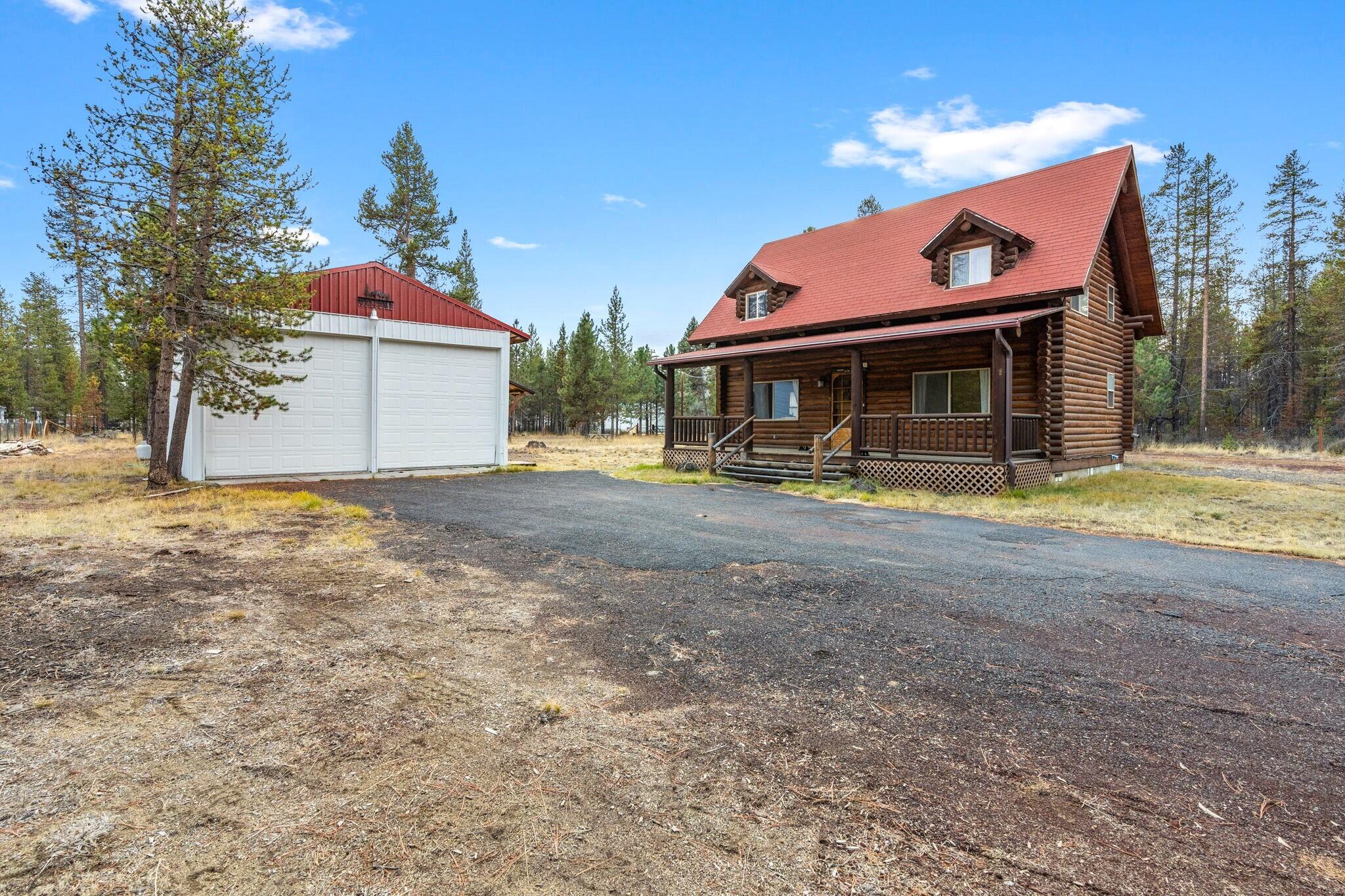 Nestled amongst the mature pines on 1.19 acres this property is home to a classic 2 bed/2 bath log cabin w/covered front & back porches, 2 bay garage, storage buildings & plenty of room for all of your toys, RVs, outdoor entertaining & more. Log home ftrs open-concept living area w/vaulted ceilings, warm wood accents, cozy propane fireplace & large windows that invite an abundance of natural light. Kitchen is fully equipped w/plenty of cabinet storage & counter space, appliances included & a cozy eating area w/bay windows. Two bedrooms & two full baths plus washer/dryer. Community water and sewer now connected!!! Short term rentals allowed. Located near La Pine State Park, Deschutes National Forest, a short drive to Sunriver Resort for golfing or dining, Mount Bachelor & all that Central Oregon recreation has to offer.  Whether you're looking for a full-time residence, vacation getaway, or rental investment, this log home offers a rare combination of charm, privacy, and convenience.