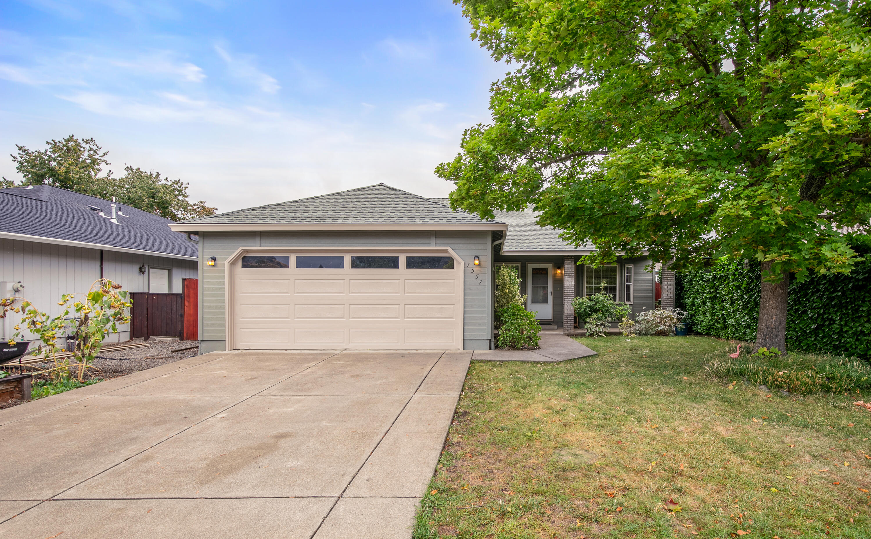 Tucked away on a quiet cul-de-sac in Talent is 1557 Summer Place.  She is picturesque with a stoic maple tree, fresh coat of paint and newer roof.  Once inside, you will find an open and bright living space brought to life by a large bay window and skylights.  The kitchen boasts oak cabinets and newer appliances.  The glass sliders beckon you from the dining area out to the back yard where you'll find a playhouse, raised garden beds, fruit trees, a water feature and unobstructed views of Grizzly Peak.  Back inside you can settle in to your large primary suite with custom built-in shelving and crown moldings.  Two additional bedrooms and a bathroom complete the package.  She's a sweet home you won't want to miss.