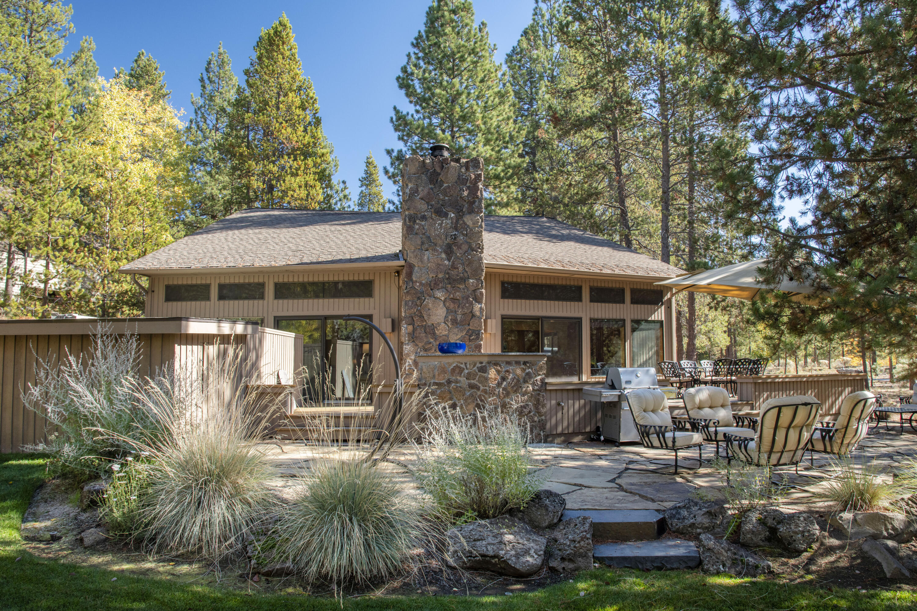 Located on an exceptional lot, with tons of rustic charm and elegant touches throughout, this contemporary cabin is the perfect spot to enjoy Sunriver. Expansive outdoor living space overlooking large common area, with wrap around deck, flagstone patio, private hot tub and large eating area. Inside you'll find a vaulted, crescent-shaped great room w/ cedar walls and ceilings, tons of windows and a lava rock fireplace, all creating a classic cabin feel - but with updates throughout including the furnace & AC in 2024.  Kitchen updates include newer cabinets, stainless appliances, slab granite countertops w/ tile backsplash. Bathrooms have been updated w/ tile floors, counters, & showers. Upstairs, two bedrooms share a generous loft, overlooking the great room. Sold fully furnished. The amphitheater is out back, SHARC is down the street, and The Village only blocks away...all within close proximity. This is a wonderful home for everyone to gather, indoors or out!