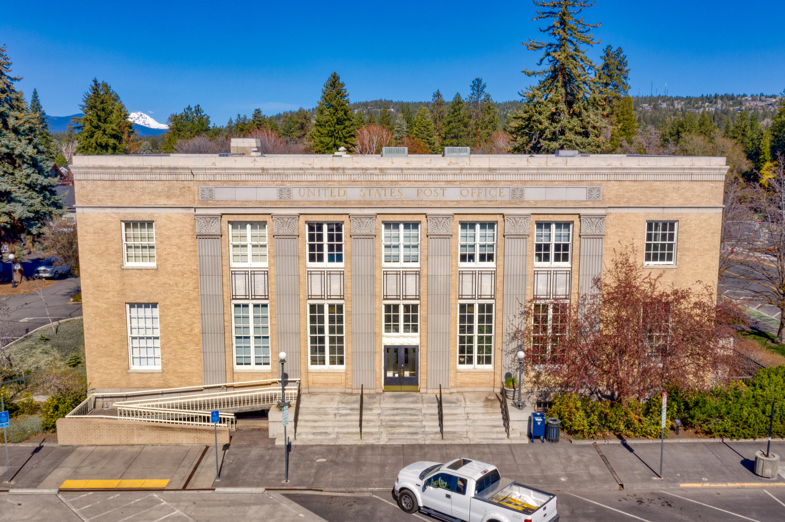 This is an incredibly rare opportunity to own a piece of Downtown Bend history. The Post Office Plaza is located inside the Commercial Business District (CB zone) which allows for a multitude of office, retail, residential and other commercial uses. Most of the suites are leased on a short-term basis with under-market rents creating an opportunity for future upside potential with a new owner. Additionally, a 36-space on-site parking lot could be developed into further building square footage, as Downtown Bend parking regulations are such that the on-site spaces are no longer needed (contact brokers for full offering memorandum).
The building was once home to the U.S. Post Office and has been transformed and upgraded over the decades since it was constructed in 1932. The three story building originally consisted of a 4,000 square foot foundation with one of the levels below grade. An addition was constructed in the 1980s. It currently has 19,352 square feet of gross building area (GBA).