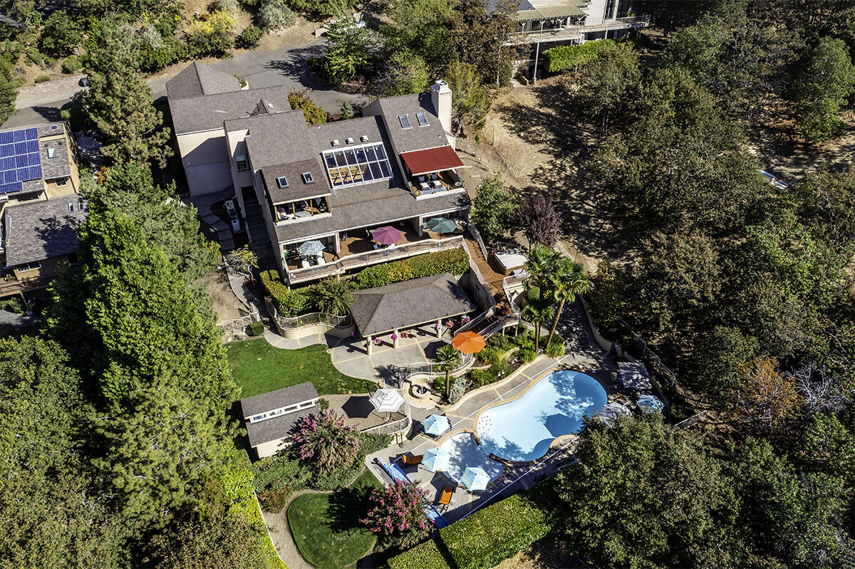 Live like you're in a private Palm Springs resort in this stunning Pagnini home with panoramic valley views on a private 0.65-acre lot in E Medford. The 3581-sqft home blends indoor and outdoor living for year-round enjoyment. The open-concept main level features a great room with a dining area, private balcony, and a chef's kitchen with soaring ceilings, a large island, built-in dining booth, and premium appliances like a Subzero fridge, Wolf double oven, and Viking gas range. The study wing includes an office with ensuite bath, marble floors, gas fireplace, and private balcony. Downstairs, a spacious living area with a wet bar separates the primary and guest suite wings, all with access to the covered patio. Resort-style amenities include an in-ground pool, new hot tub, huge covered outdoor kitchen with pool bathroom, and beautifully manicured grounds. The 5-car garage offers ample storage. Plus, there's a finished garden shed and large storage room.