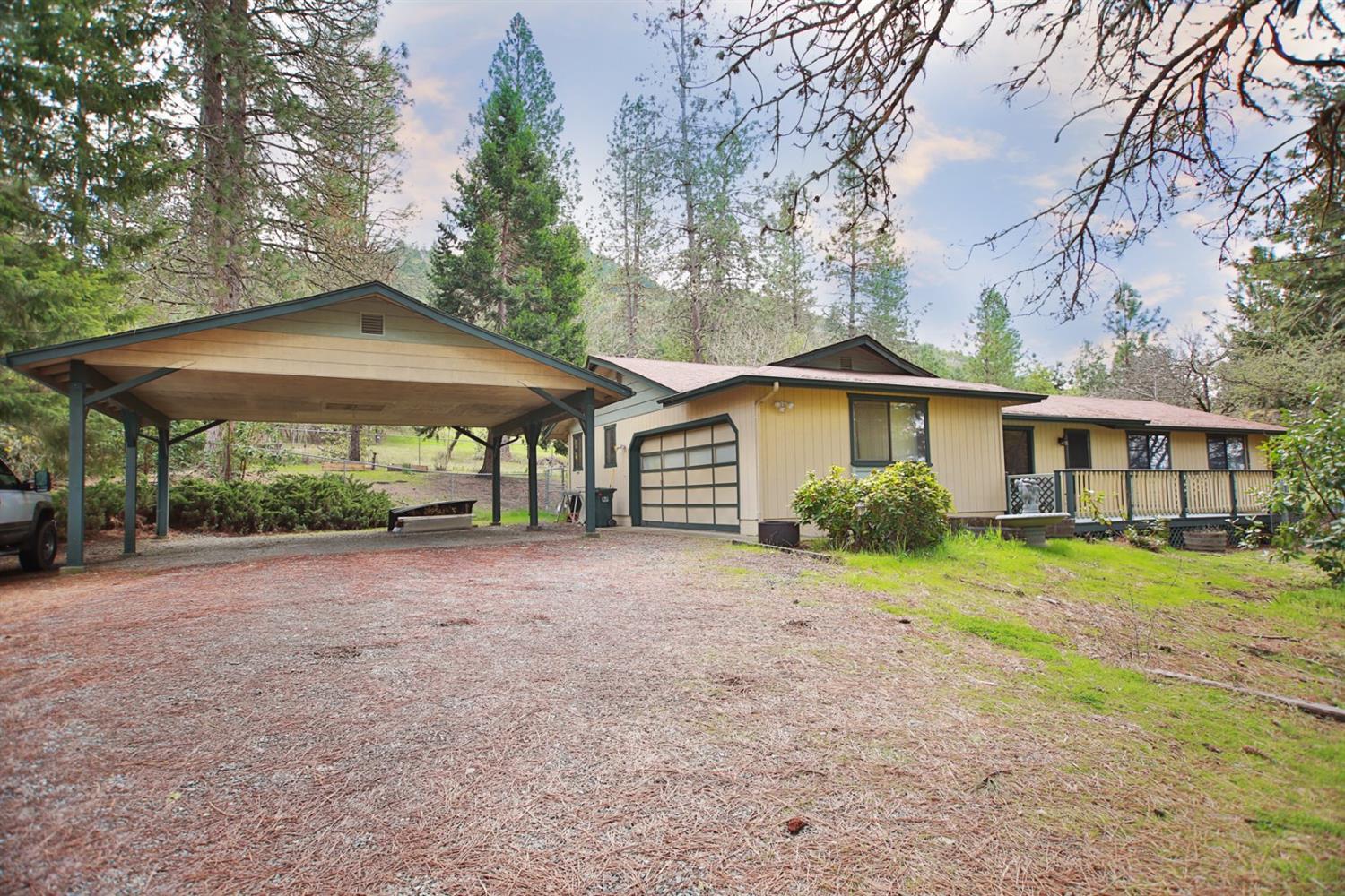 Come find the peace and quiet you've been craving in this wonderful home set far back from the road on a beautiful acre of land shaded by towering pine trees. This turnkey home features vaulted ceilings, a large open kitchen with corian countertops and stainless steel appliances, two large living rooms, one with a great picture window looking out at the parklike front yard, the other with a brick hearth and new certified woodstove, plenty of room in the master for a king sized bed and remodeled bathrooms. Outside you'll love the decks in both front and back, fully fenced back yard, lush green lawn bordered by daffodil and irises, raised garden beds and walnut, plum, crabapple and cherry trees. 2 car garage and 2 car carport give plenty of room for parking and storage. Don't miss it!