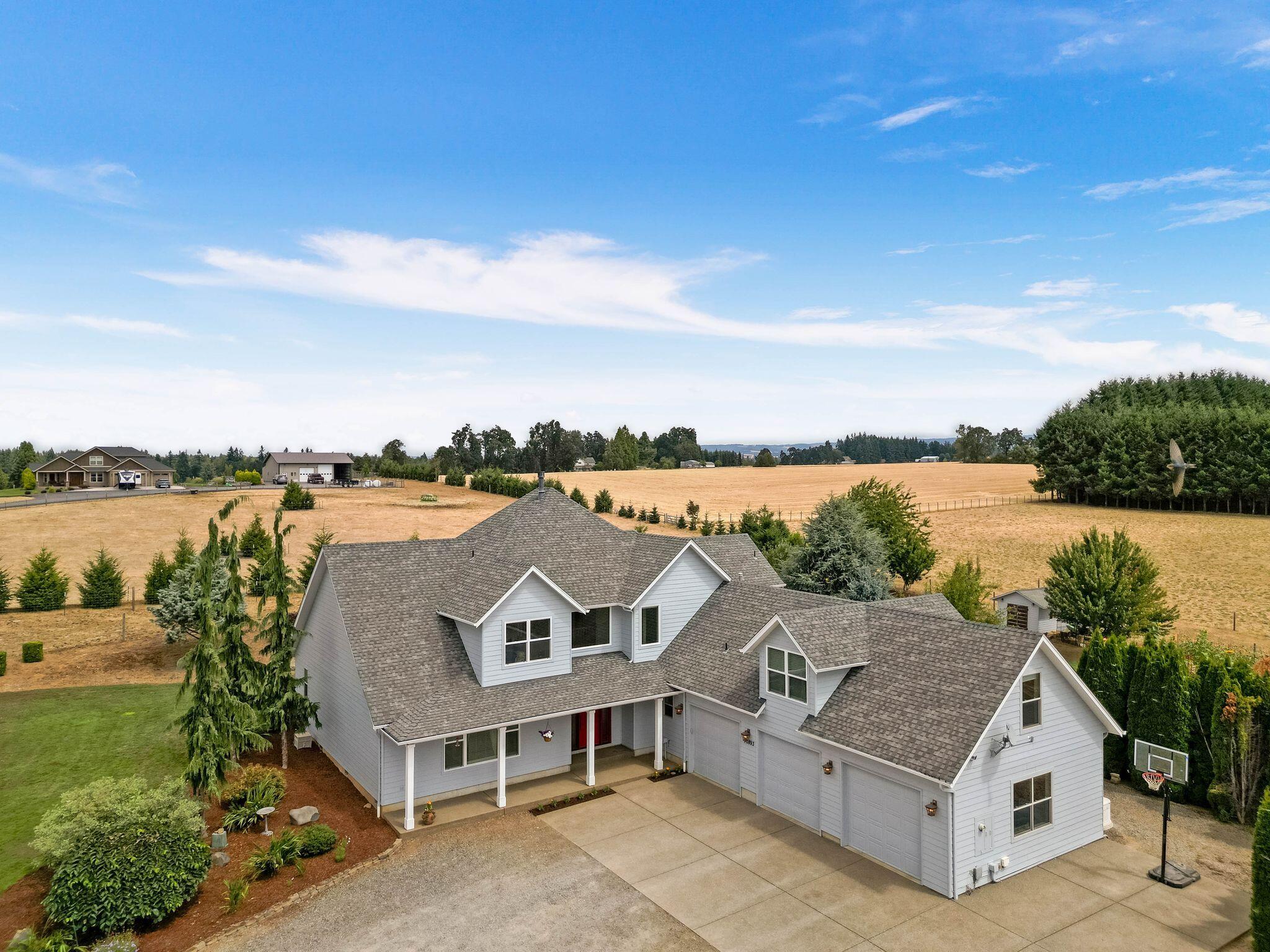Exceptional custom-built home nestled on 5.89acres! Spacious entry leads into vaulted great room w/massive picture windows & central built-in fireplace. Open-concept kitchen ftrs gleaming hardwood floors, granite counters, brkfst bar island, ample cabinetry, & seamless flow into the dining areas. Spacious main-level primary provides convenience & privacy, w/walk-in closet, soaking tub & tiled shower. JR suite + 2 addtnl bedrooms w/3rd shared full bath + double bonus rooms upstairs—potential 5th bedroom, guest suite, etc. Oversized 3 car garage, 60x40 shop—equipped w/two 16-foot doors & covered hay storage. Raised garden beds, matured fruit trees, & tons of space for expansion. Fully fenced & cross-fenced, NEW auto-blinds in home, & a 24KW propane Generac generator system, ensuring peace of mind & uninterrupted power year-round. This property offers the perfect balance of luxury, utility, & lifestyle in one of the area's most sought-after communities.