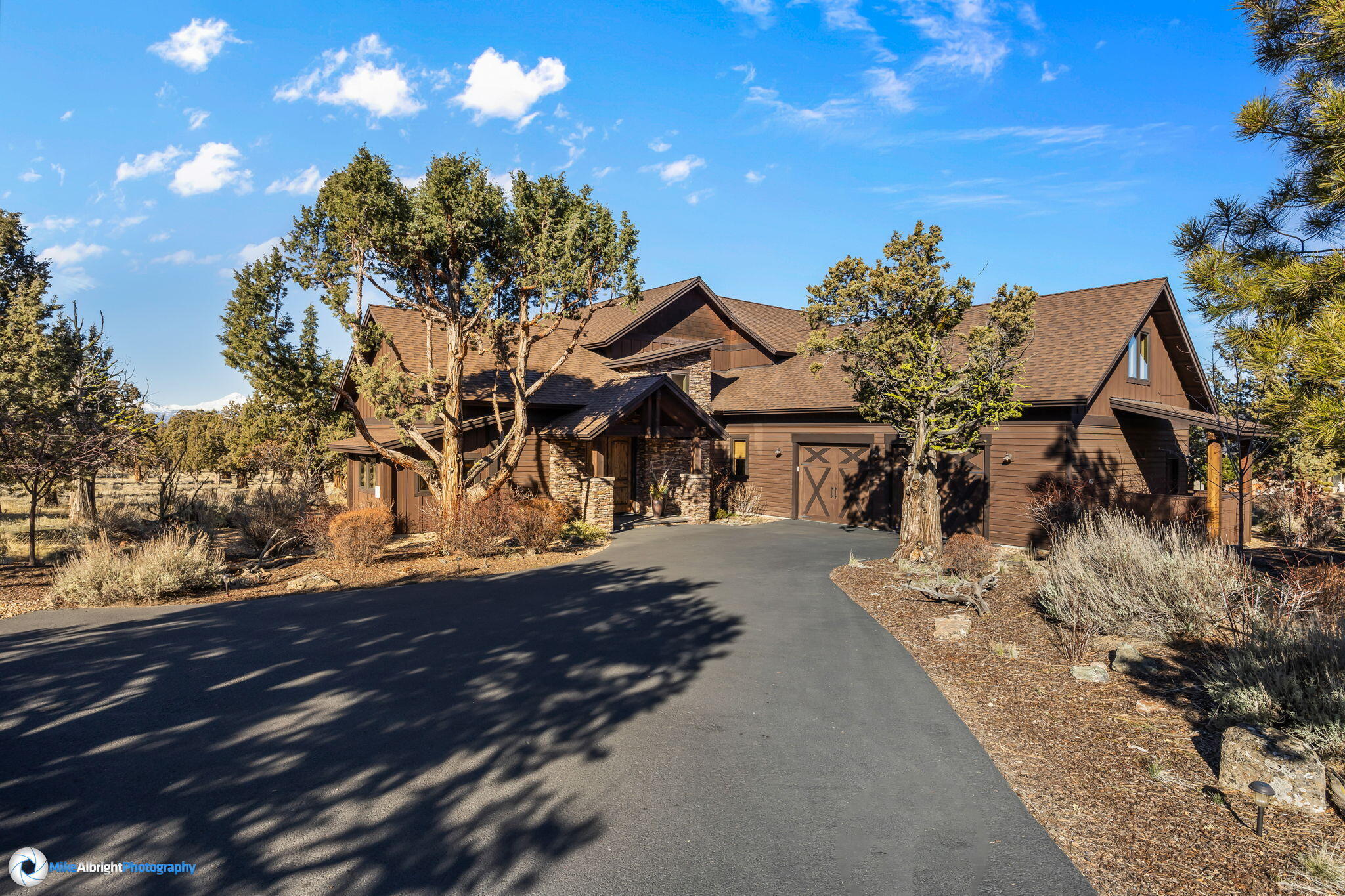 This Gorgeous custom home with panoramic views of the Cascade Mountains is perfectly situated at the end of a cul-de-sac on the West Ridge in Eagle Crest Resort and backs to common space and BLM land for maximum privacy.
This home has a Tuscan feel with its black walnut hardwood floors, distressed wood beams, hand troweled walls, built-ins, wood wrapped windows and trim, and solid core doors. The double-door entryway leads to the covered paver deck where you will find ample space for entertaining. The kitchen is a cook's dream with slab granite countertops, a gas cooktop, and a walk-in pantry. The luxurious main level primary suite boasts a walk-in closet, jacuzzi tub, walk-in shower, a double-sink vanity and opens to the back deck. On the upper level you will find a bonus room with views of the Cascade Mountains, a private balcony, an adjoining wet bar with a wine barrel ceiling,  two guest rooms and two full baths. Oversized two-car garage and covered exterior storage area.