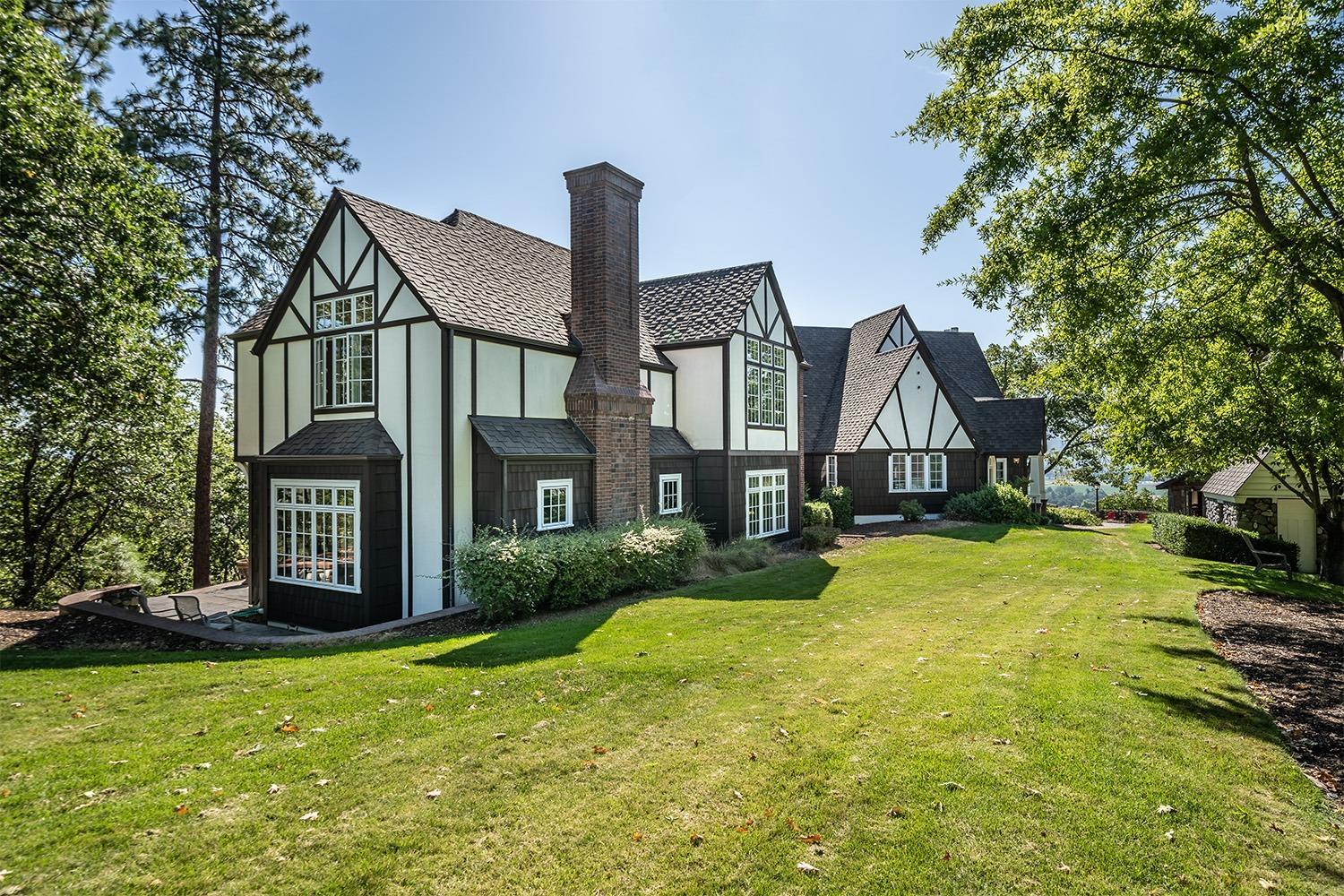 Amazing 7-acre estate property w/magnificent valley views & a large, wonderful Tudor style home. Located just outside Historic Jacksonville this gated & private 5 bed, 4.5 bath home beautifully blends indoor & outdoor living making it perfect for entertaining. Vintage charm & finely finished architectural details are seen on each level w/boxed beams, hardwood floors, 2 spiral staircases, soaring ceilings & picturesque Tudor arches. Stunning master suite w/a fireplace, wet bar, sitting room, 2 walk-in closets & 2 separate sleeping areas w/convenient elevator access. Luxurious ensuite w/heated travertine floors, double headed shower, dual sink vanity & soaking tub. Expansive family room w/a soapstone Tulikivi heater, wall of windows & separate game area. Light & bright kitchen w/slate floors, painted white cabinetry, pantry & eating bar w/deck access. Charming stone pool house w/a half bath, large inground pool, lighted sport court, oversized 2 car garage, carport & asphalt driveway.