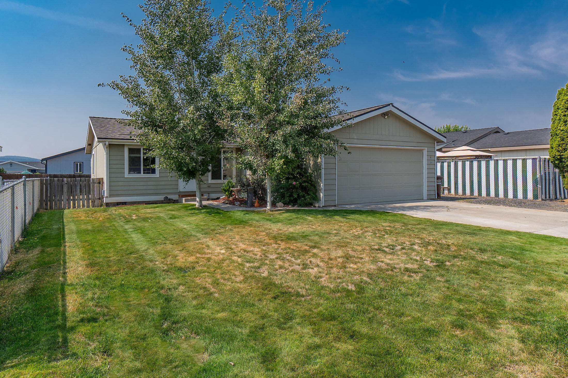 This well-priced 1999 MFG home has new roof, plus a heat pump for your comfort!  It's an eat-in Kitchen with nice tile floors, SS appliances & a sliding glass door to your backyard. The open floor plan flows into the living room with vaulted ceilings, making the home feel more spacious than it is. The laundry room has a washer/dryer & leads out to the 2-car garage.  You'll find the same attractive tile floors in the primary bedroom ensuite & guest bath, shared by the 2 other bedrooms.  There's a finished 2-car garage, with an opener, & a workbench for your projects. The front yard boats gutters & landscaping.  The backyard is fenced on 3 sides, has a storage shed, a patio & is full of potential for someone with a green thumb! You could even put a garden bed or two in the side yard to grow flowers or veggies. With a full price offer, seller will credit buyers $3,000.