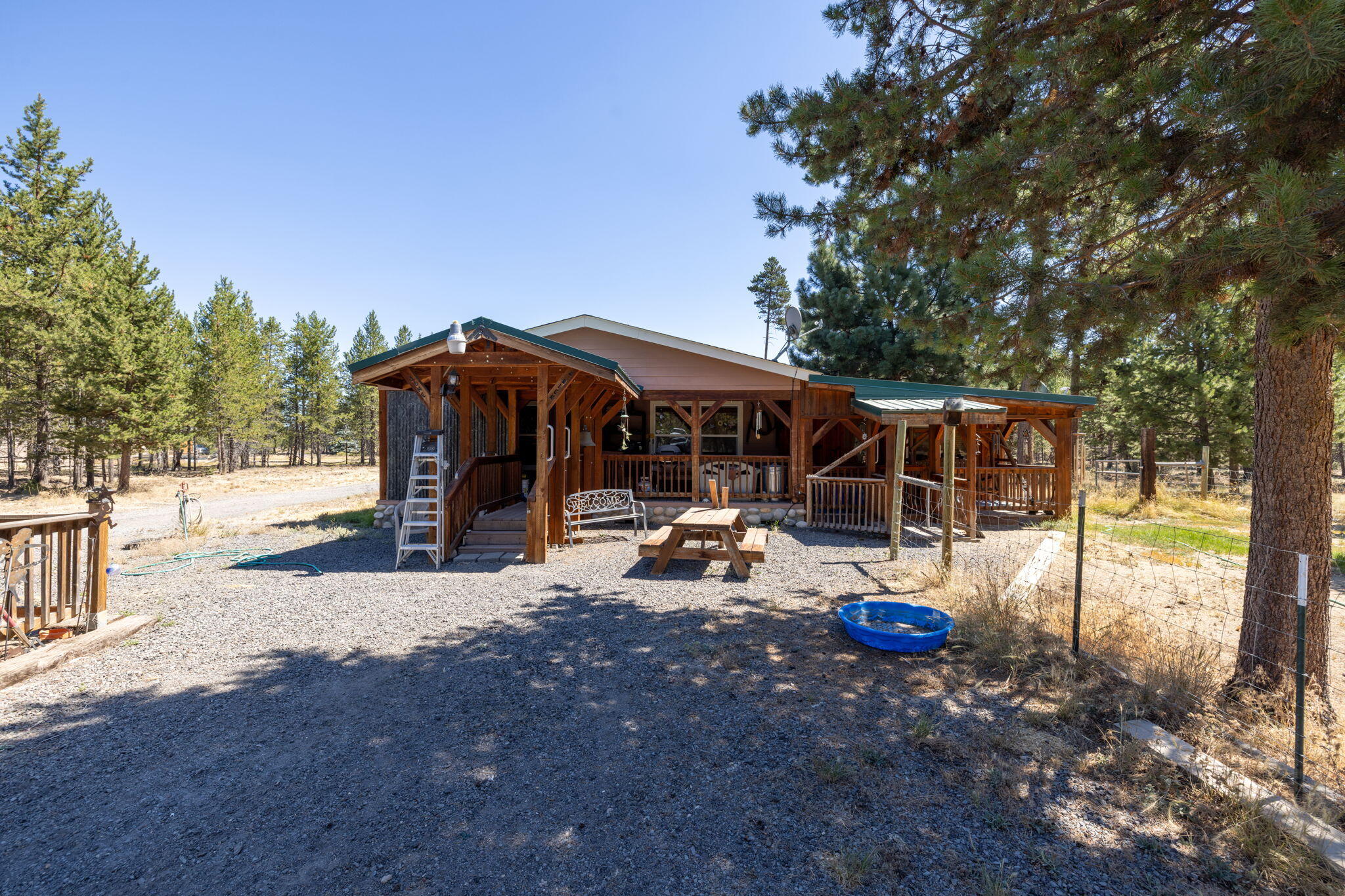 Enjoy peace and privacy on over 4 acres with this comfortable 3-bedroom, 2-bath home offering space, flexibility, and a true country setting. The covered front porch is perfect for morning coffee, evening conversations, or simply taking in the surroundings. Inside, an additional family room with a separate entrance provides versatile options for a fourth bedroom, guest area, or a secondary living space. A spacious workshop offers ample room for storage, hobbies, or projects, complemented by a carport, tractor bay, and convenient pull-through driveway. Water access throughout the property supports gardening, animals, or future expansion. Located in a welcoming rural community, this property blends functionality with tranquility. A heat pump ensures year-round comfort. Ideal for those seeking room to grow, space to work, or peaceful country living.