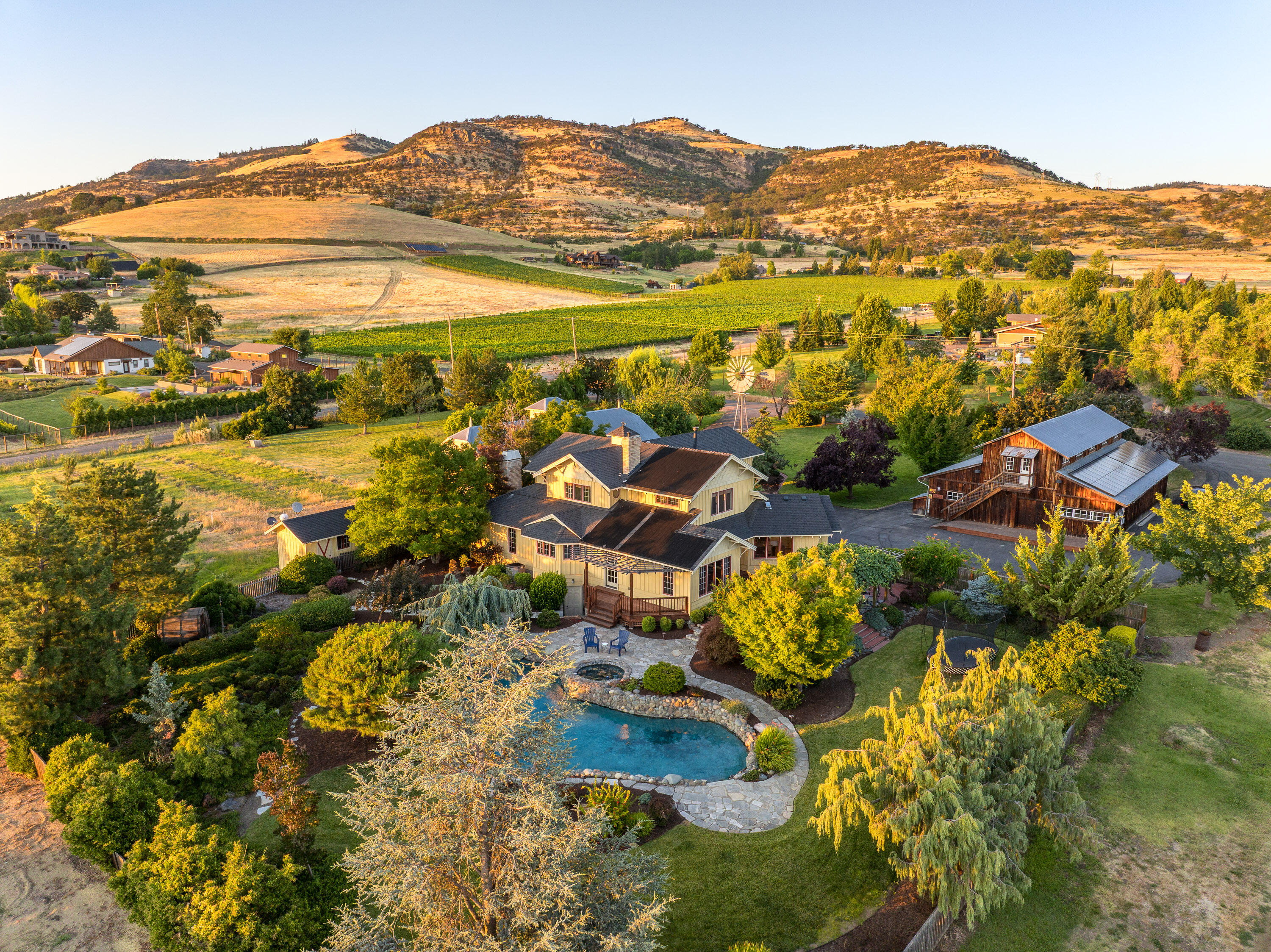 Located between Ashland and Medford, 4050 Royal Crest sits in one of the region's most desirable rural areas. The centerpiece of this 34-acre property is a custom farmhouse-style home that is full of character, with warm finishes and multiple living and dining spaces. The updated kitchen features a large island, great views and professional-grade appliances. The primary suite features vaulted ceilings with wood beams, a woodstove, incredible views, and a large private bathroom. Designed for indoor-outdoor living, the home opens to a brick patio, pergola, custom pool, and mature landscaping. Outbuildings include a three-car garage with additional utility spaces and a rustic barn with charming upstairs guest quarters. Currently a producing pear orchard, the irrigated land is primed for vineyard conversion, equestrian use, or as a small ranch. Gravity pressurized TID Water Rights. A rare blend of location, infrastructure, and potential, all framed by panoramic views of the Rogue Valley.