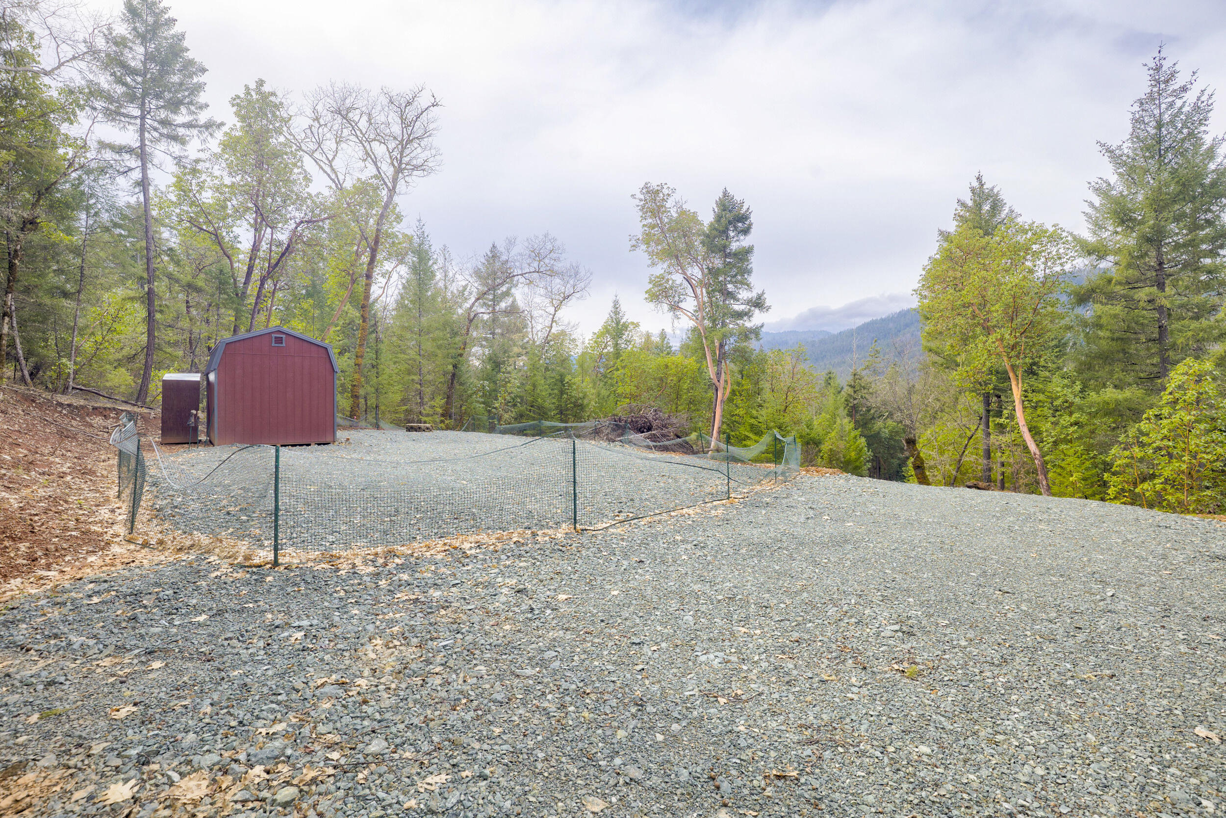 Discover the perfect canvas for your dream home on this peaceful and private 2.53-acre parcel nestled among mature trees with mountain views. The homesite and driveway are already cut in and graveled, offering easy access and a head start on building. Enjoy seclusion with the property backing up to over 650 acres of BLM land—ideal for hiking, wildlife watching, and exploring. Just down the road, you'll find Rogue River access at the Ferry Boat dock. A storage shed is included for your convenience. Located only 15 minutes from downtown Grants Pass, you'll have quick access to shopping, dining, and services while still enjoying the tranquility of nature. Whether you're planning a custom build or seeking a peaceful retreat, this property offers the best of both worlds. Come build your dream home here!