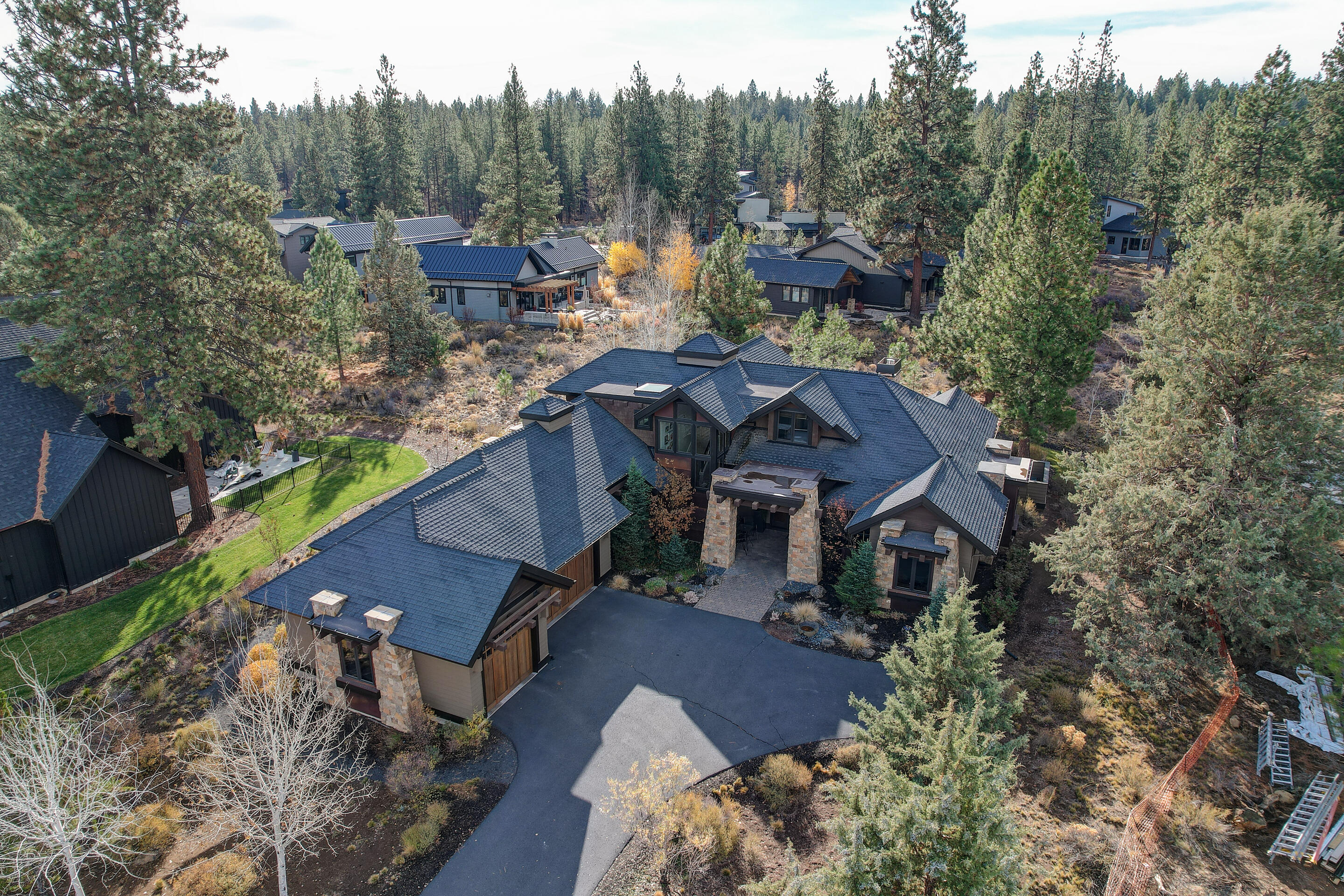 This stunning NW contemporary home sits tucked back on a quiet cul-de-sac in the sought-after Tetherow community.   This home was designed around the concept of gathering and entertaining. The vaulted great room plan is graced by a striking rock fireplace wall, updated hardwood floors and wood paneled ceilings.  The chef's kitchen has quartz countertops, double ovens, a 6-burner Viking range, two dishwashers, prep sink and a separate wet bar with 2 beverage fridges.   Wine enthusiasts will love the luxury wine refrigerator as a focal point around the dining area that opens to a cover patio with outdoor gas fireplace and built-in BBQ area. There are two main level primary suites and an office on the first floor of this spacious home and two additional bedrooms anchoring an open bonus area upstairs opening to an upstairs enclosed deck. The level lot backs to common space enhancing privacy until you join neighbors at the community restaurants, 2 pool, gym or miles of accessible trails.