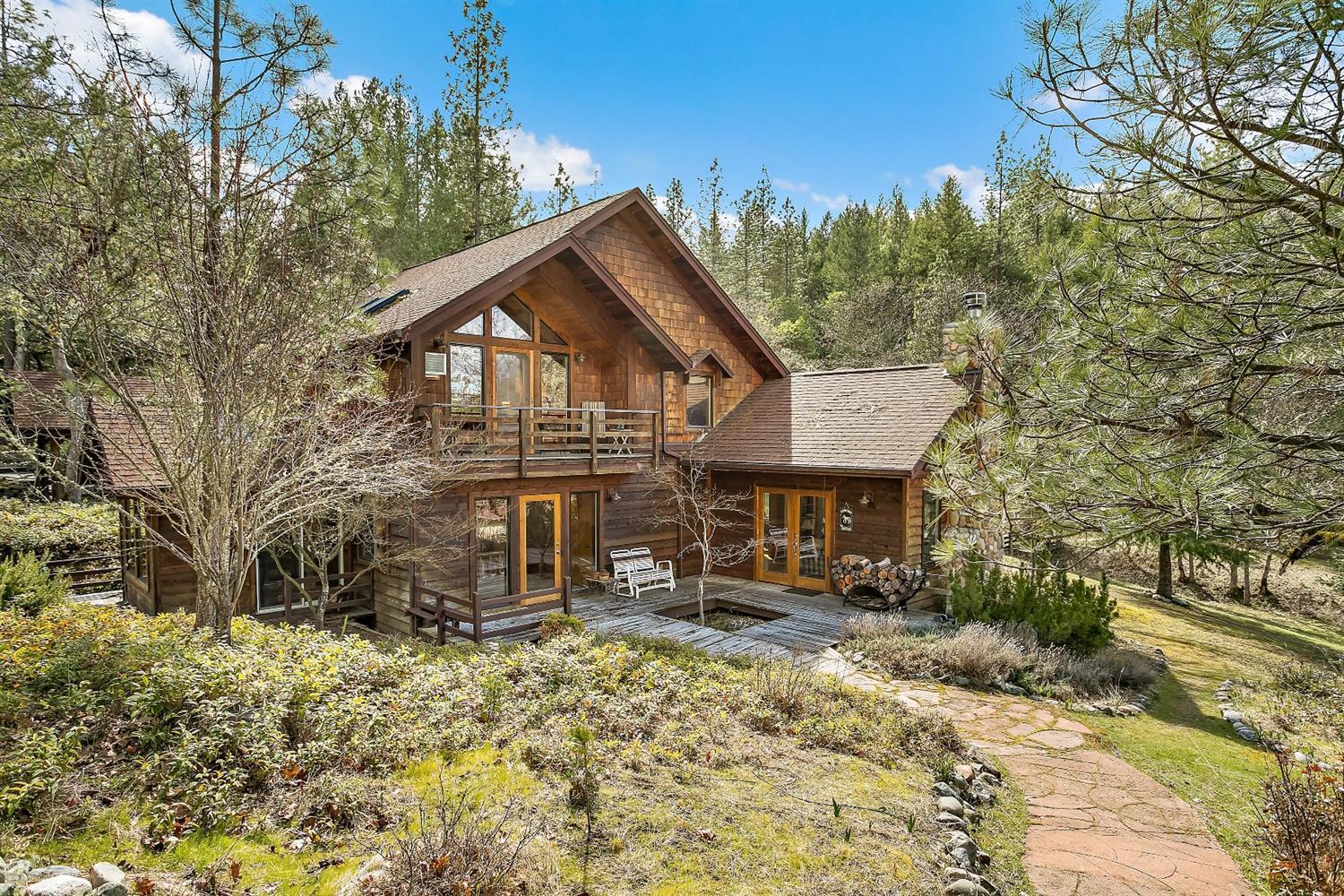 Lodge-style home sits on 20 gorgeous, private & quiet acres w/horse set-up & BLM access all less than 15 miles to historic town of Jacksonville. Transom windows soar to exposed beam vaulted great room ceilings with stunning private views of forested setting! Remodeled kitchen w/granite island, quartz counters & newer appliances. Wood floors lead to both picturesque family room w/river rock fireplace & more views from formal dining room. Enjoy expanded living under huge oak tree canopies over huge deck w/eating bar & newer spa. Vaulted master w/private deck, skylights & remodeled bath w/dual sink granite counter vanities & tile floor. 864 sq ft 3-stall barn w/lg tack room w/fenced lg corral & compacted area for round pen w/easy access to BLM. Fenced organic raised bed garden & shed, arbor patio along seasonal creek/pond, meditation shelter. Garage w/shop area. Office loft. Guest bath w/jetted tub, heated floor & oversized rock shower. All information deemed reliable, but not guaranteed.