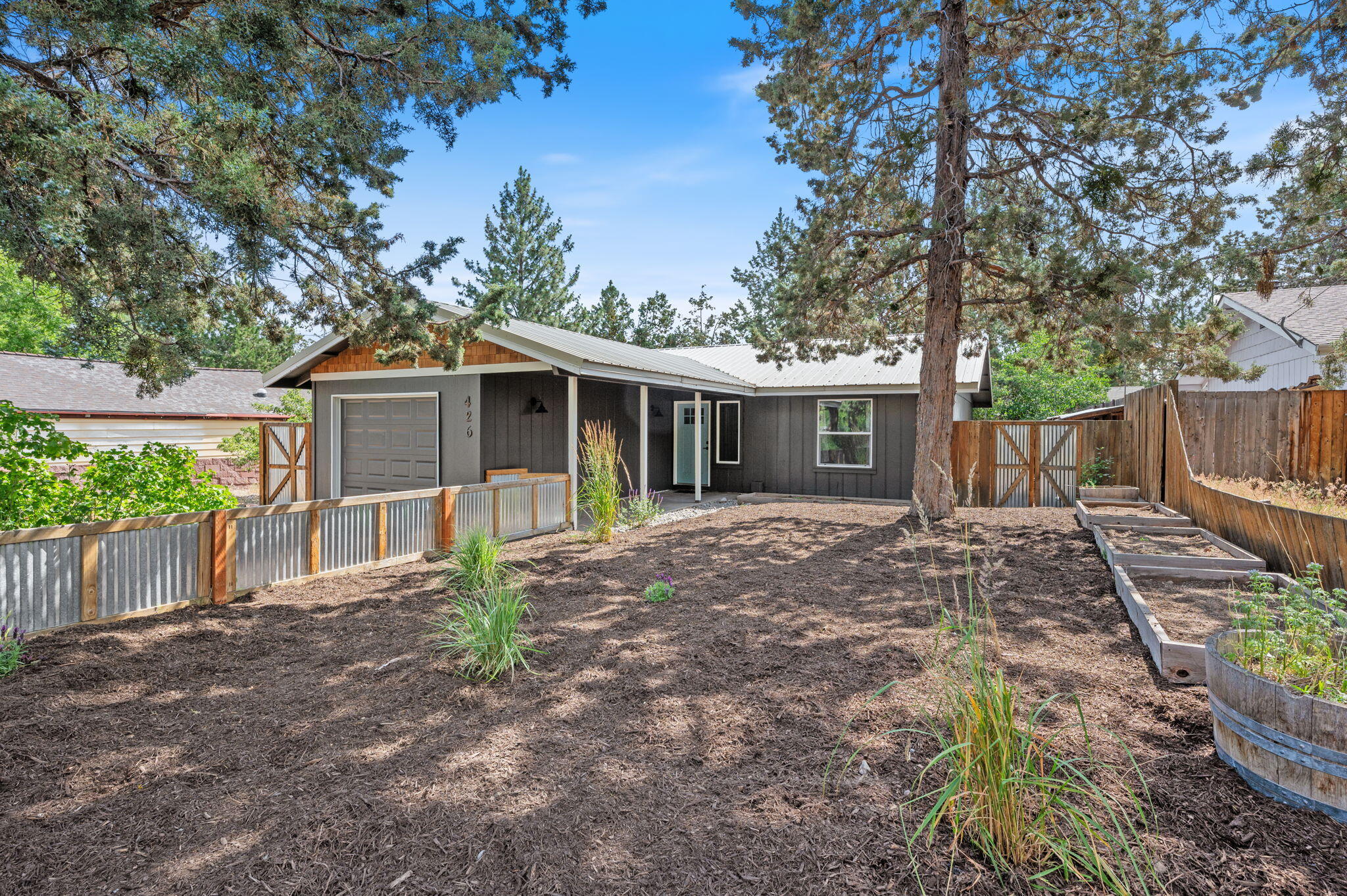 This well-kept 2 bed, 1 bath home is located in the heart of Bend! With fresh interior and exterior paint, new carpet, and an open layout, it is move in ready. The living area features vaulted ceilings and a wood-burning stove that adds both warmth and character. The kitchen includes custom open shelving made from reclaimed wood from Bend's original Old Mill. The spacious primary bedroom offers his and hers closets, and the second bedroom is perfect for a guest room, office, or kids room. Outside you will find a fully fenced yard with beautiful quaking aspen trees and native landscaping. An attached garage adds convenience for storage and off-street parking. The raised garden beds and small chicken coop are ready to be used! Covered entryway and back deck offer plenty of outdoor spaces to relax. Property is zoned RM which could provide flexibility for future options. - buyer to verify all uses.