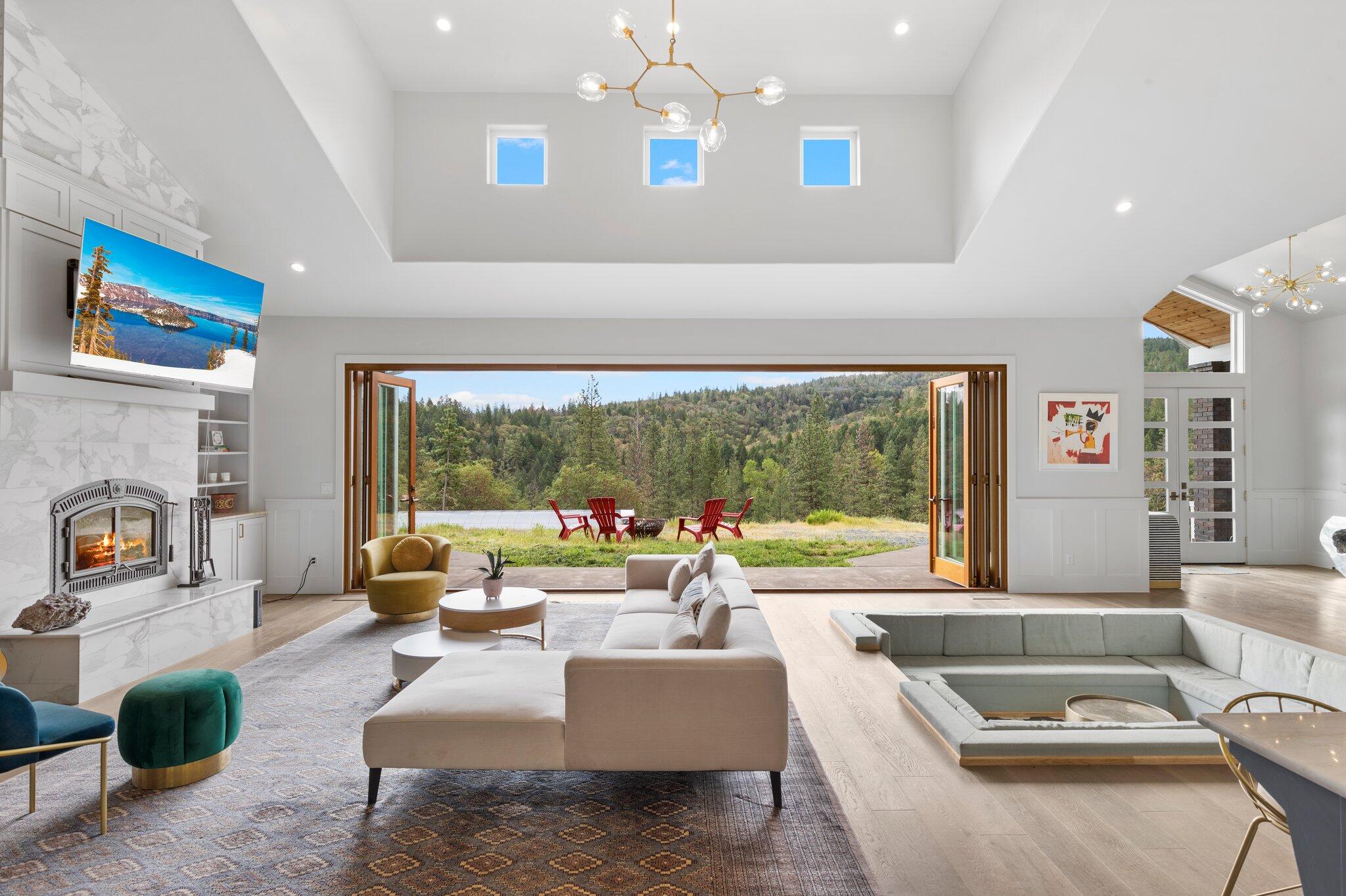 This Incredible custom home is located conveniently near Jacksonville, OR and is hitting the market for the first time ever. Built in 2017, this luxurious property boasts 3,471 sq ft, 3 bedrooms, 2 bonus rooms, 2.5 bathrooms, a 3-car garage, large shop, 80'x24' permitted greenhouse, propane generator, R/V pad, walk-in pantry, and chef's kitchen. The great room is spacious with natural light, a pit sofa, and bi-folding glass doorwall that opens entirely with views to the mountain/trees. The downstairs primary bed/bath suite features his and her walk-in closets, separate laundry, and a grand bathroom with a soaking tub, heated floors, steam shower, custom dry sauna, and dual vanity sinks.The property is fully fenced with electric gate access, unfinished pond, concrete retaining walls, and large built-in garden beds with ample space for  parking. Overall, this custom home with its extensive features and finishes is sure to be appreciated by residents and guests alike.