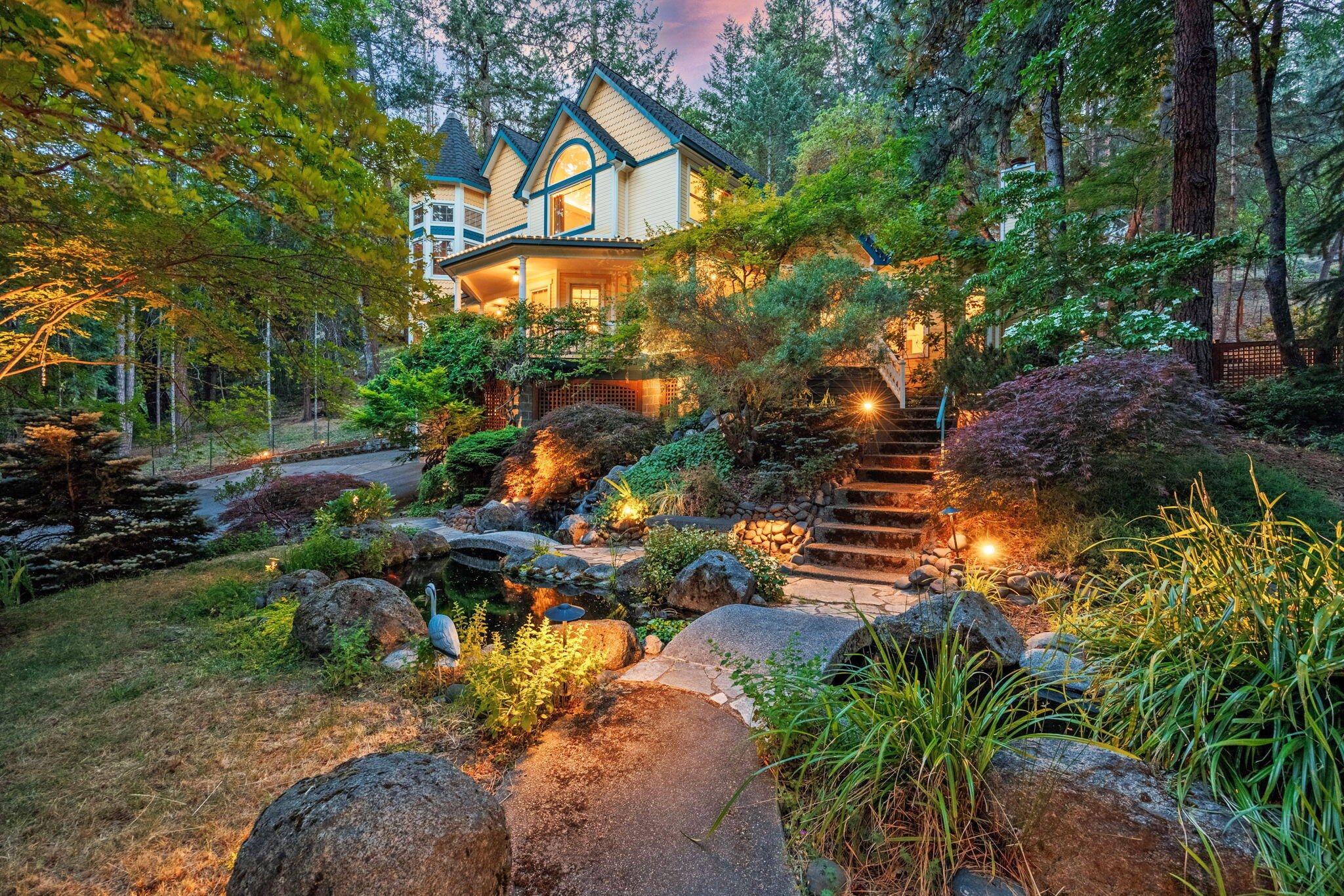 Prime gated estate on Ashland's famous Granite St tucked off the road across from Lithia Park! This Neo-Victorian sits on a .53 acre lot w/ TID irrigation surrounded by lush landscaping and a Japanese garden. Awaken to birdsong and fall asleep to the trill of frogs and the gentle splashing of the Koi pond waterfall. Main level includes the great room, dining room, living room w/ gas fireplace, full bath, office or bedroom, wraparound covered porch, and a 9-person recessed hot tub on the rear Cedar deck. Large gourmet kitchen includes a SubZero fridge, island w/ downdraft range, eating bar, dumbwaiter from garage, and a turret sitting area on both levels. This is an entertainer's ideal setup! Upper level has one bedroom, another en-suite bedroom with common access bath, and the luxurious owner's suite w/ a double vanity, jetted tub, and a large tile shower. Entering this private oasis feels like you've left town yet hiking trails, dining, and Shakespeare are just beyond the front gate.