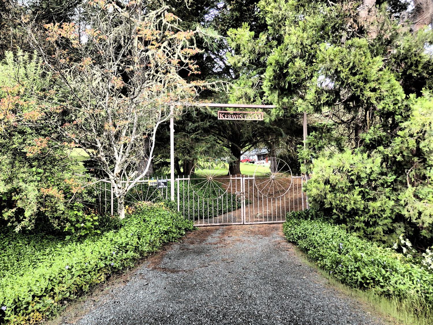 Mini-farm w/many possibilities. The entry is gated for extra privacy. A total of 5.06 acres w/water rights from an unnamed year round stream that feeds a pond w/spillway. Lush lawns, fruit trees, walnuts, fenced garden area, multiple pastures, grapes, roses, lilacs. Shop & large historic barn w/4 stalls & tack room. Level area near barn formerly held an arena. The older single-level home is cozy, w/wood-paneled tile-floored sun room, dining/family area, den, kitchen w/wood stove, living room w/FP w/insert & fan, 3 bedrooms, 2 baths, built-in's, mud/laundry room, screen porch & attached 1-car garage w/storage & shop area, utility sink & 1/4 bath. The home sits at the back of the property w/plenty of room to roam. Call for your personal tour, & welcome home!