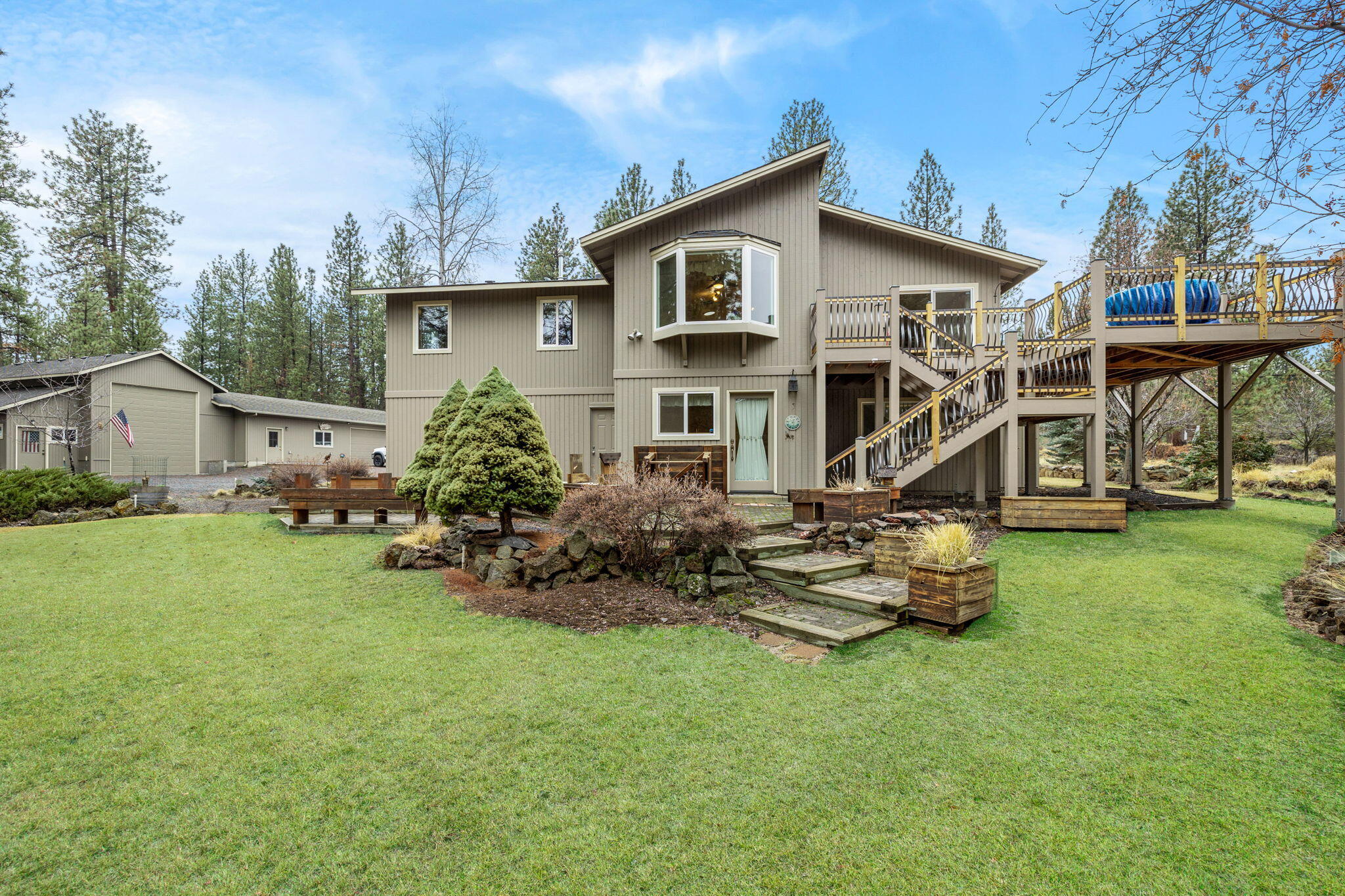 In a private, parklike setting on nearly 2 ½ acres this meticulously maintained 5 Bedroom home features a separate RV Garage, Workshop, & a 2-vehicle garage, as well as an attached garage, along w/ beautiful landscaping and gardens. The lovely home benefits from amazing interior spaces that take in a large great room with cozy fireplace, a remodeled kitchen with solid surface counters, island/breakfast bar, a large butler's pantry and a cheerful dining room overlooking the secluded garden oasis & lush forest surroundings. This home provides a place for everyone to spread out and relax in their own private spaces, including a serene primary suite, a cheerful sewing/craft room, a lower-level guest bedroom & another bedroom currently serving as a spacious office & bonus room, while the second level encompasses a private sitting room alongside two additional guest rooms. The expansive outdoor deck offers multiple opportunities for entertaining & enjoying the peaceful outdoor surroundings.