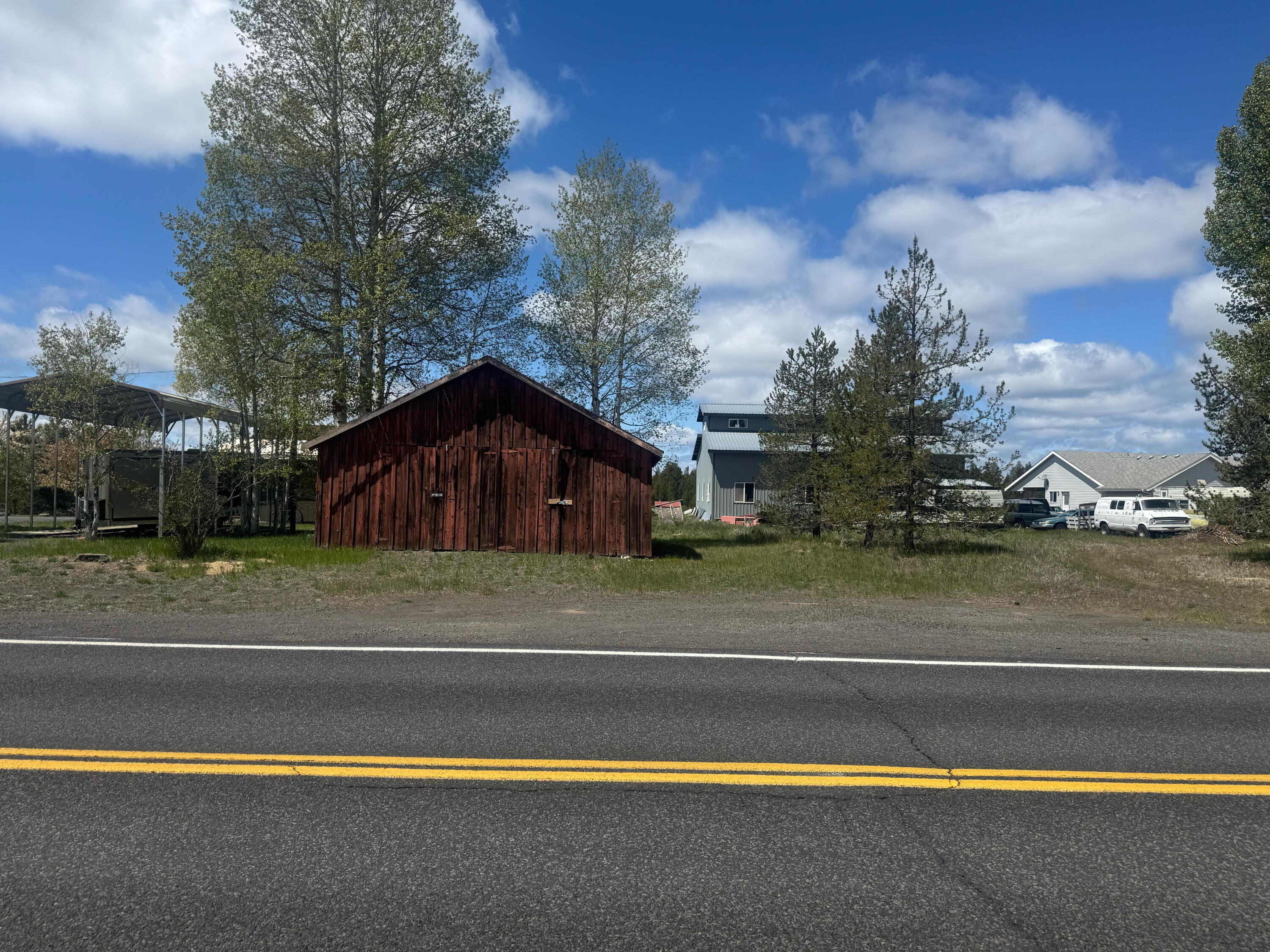 This versatile 0.38 acre lot is ideally located just off Highway 97, offering excellent visibility and easy access for future commercial or residential use. With flexible zoning, this property is perfect for a wide range of development opportunities. Site improvements include covered RV parking with full hookups, making it ideal for interim use. Electricity, gas and city water and sewer are on the property.