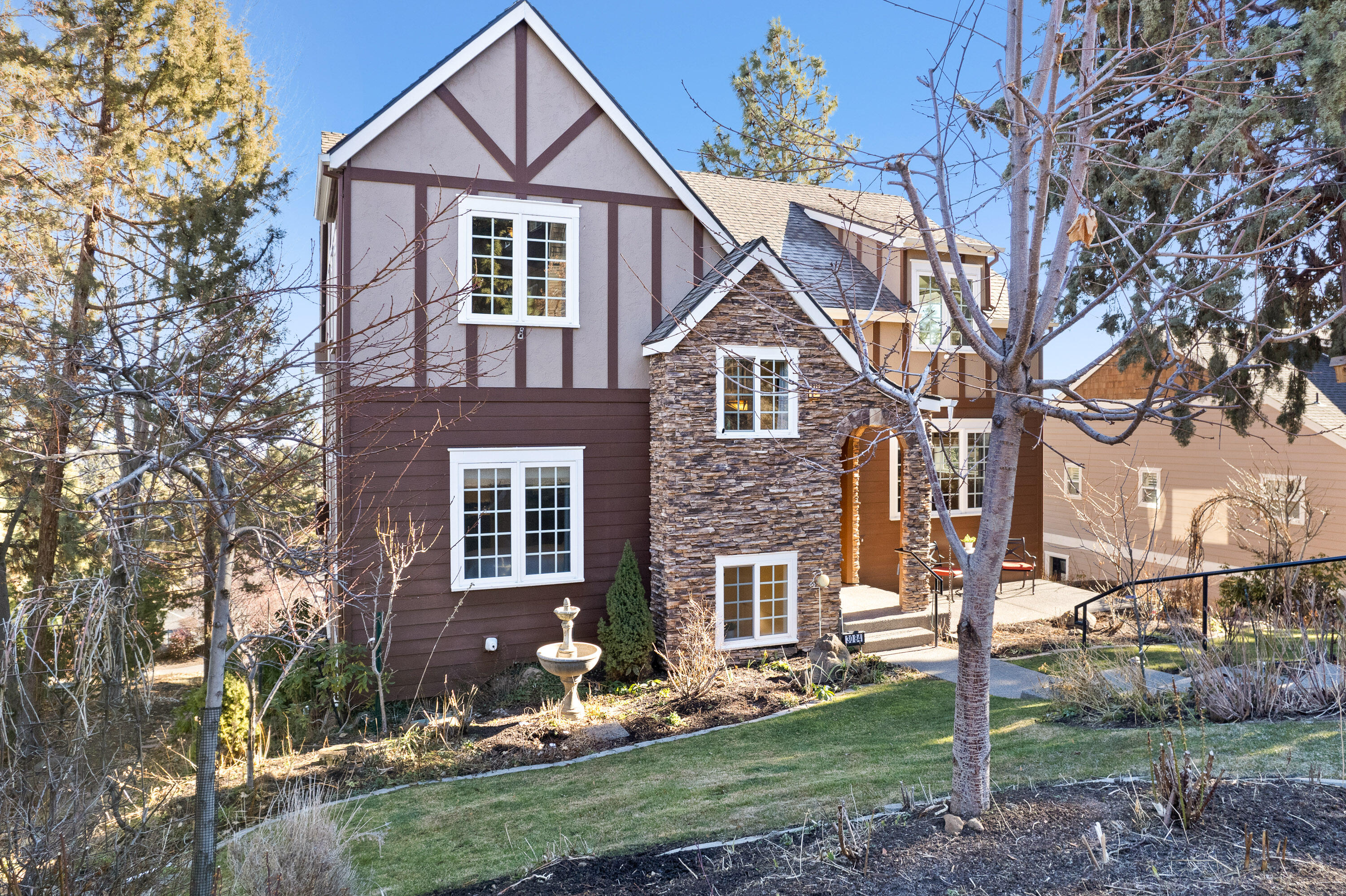 Awbrey Village Tudor home with gorgeous Northeasterly VIEWS!  The open great room with a gas fireplace and a cozy dining area opens to a large deck perfect for enjoying the morning sunrises and evening city lights. The Kitchen has a large island, granite counters, cherry cabinets, stainless steel appliances, built-in refrigerator, pantry, built-in desk and a dumbwaiter from garage.  The main level includes a formal dining room and 4th bedroom/office with French doors and access to a full bath.  Upstairs there are 2 guest rooms and a primary suite with views, gas fireplace, walk-in closet, bath with jetted tub and cultured marble shower. Features include hardwood and tile floors throughout (NO CARPET), built-in speakers, central vac, Hunter Douglas blinds and AC.  Huge alley entrance 3 car garage (approx 1200 SF).  Stunning outdoor space with lush landscaping to include a garden area on the south side, a greenhouse and a front patio. Awbrey Village Park with playground is just down the alley.