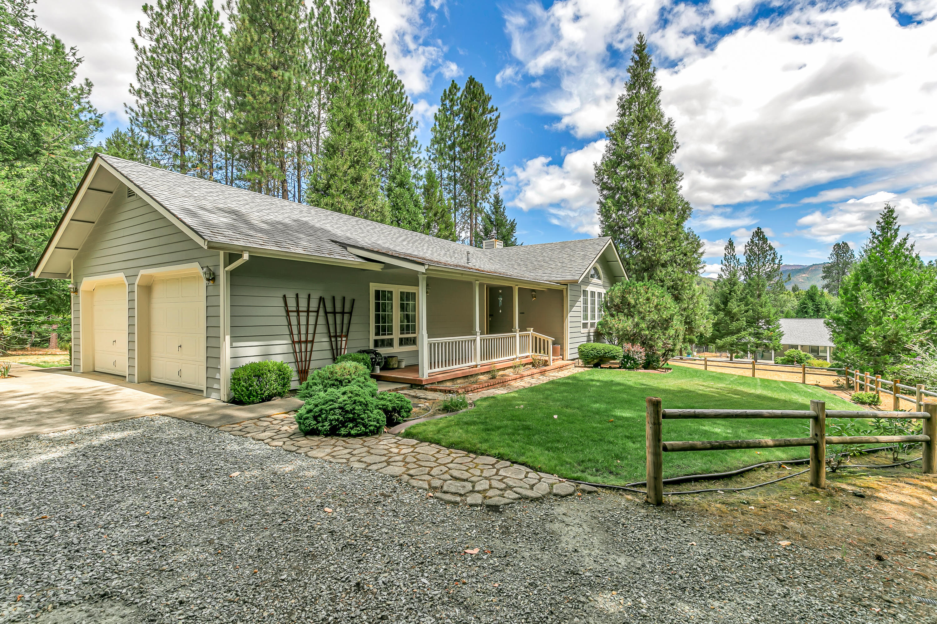This inviting 3 bedroom 2 bath home offers 1,588 sqft of comfortable living space set on 2.17 peaceful acres. A vaulted ceiling and cozy wood-burning fireplace create a warm, open feel in the living room. The kitchen has classic tile countertops, a dedicated coffee bar, and sliding doors that open to a spacious deck. This outdoor space is also accessible from the primary bedroom, perfect for relaxing or entertaining. The primary suite includes a walk-in closet and tile shower/tub combo. Plenty of parking with an oversized 2 car garage, 864 sqft detached 2 car garage/shop, and space for an RV or boat. The shop features a half bath, breaker box with 220v outlet, and brand-new roof with skylights. Combining functional amenities with plenty of room to grow, this property is the ideal place to create the home and lifestyle you've always envisioned!