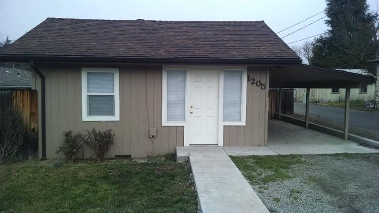 Sweet little doll house has new roof & gutters, new flooring, some new plumbing, new kitchen cabinets, new double-pane windows - $50,000+ in recent renovations. Was 2 bedrooms, but now a big open 1 bedroom suite, 1 bath plus a cute little dining nook and separate laundry room. New cement walkways and in the carport and back porch areas. City recently installed storm drains and paved the alley. Lots of room off the alley to build a shop or garage behind the house. Check with city of Medford for other possibilities in SFR-10 zoning. Charming original high ceilings and moldings add to the feeling this is a much larger home than it looks. Newer water heater (electric) as well.