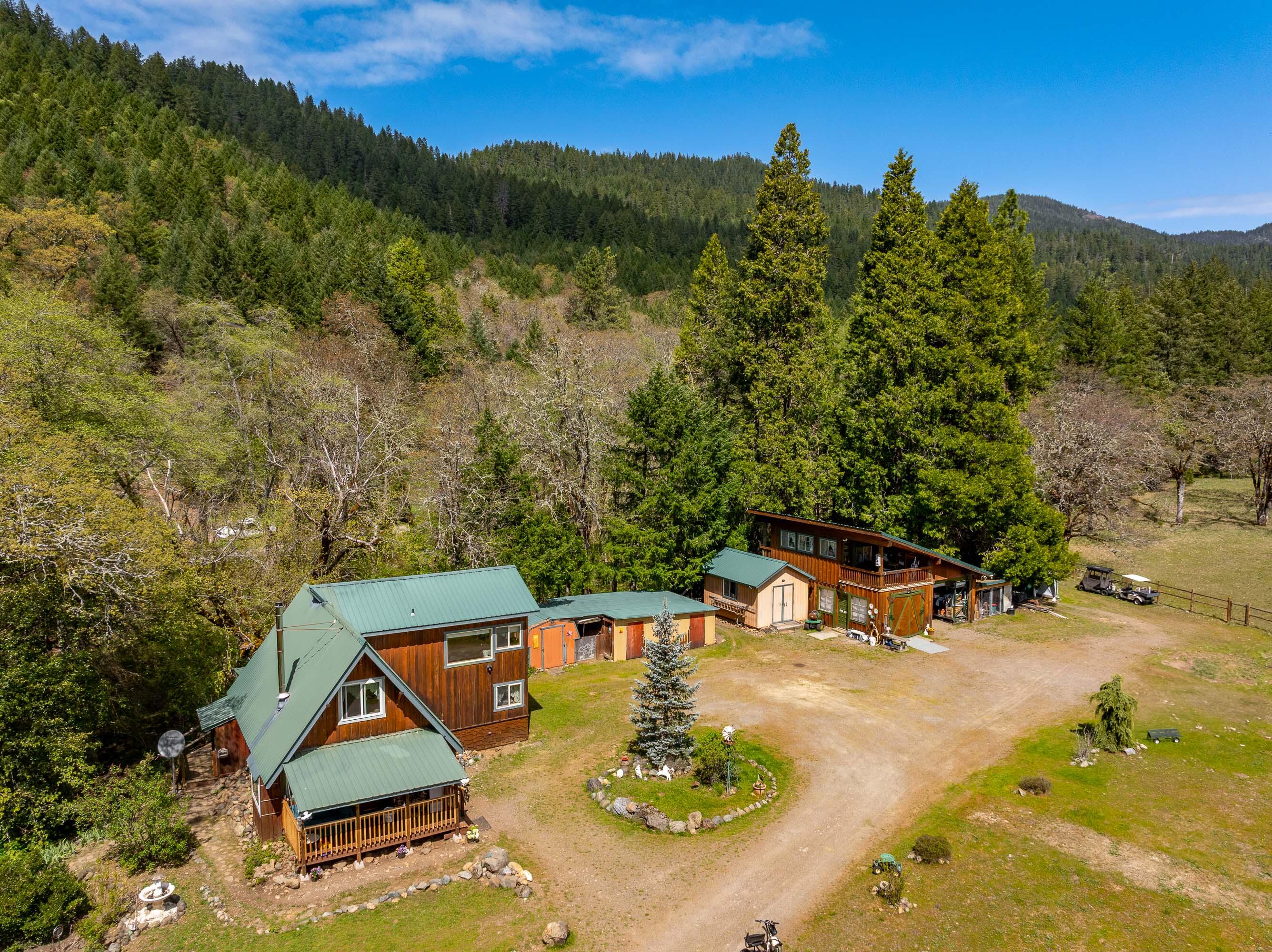 Discover your private retreat with breathtaking views! Nestled just a short distance from the Kerby Peak trailhead, this charming 2-bedroom, 1.5-bath home offers 1,139 sq ft of updated comfort and versatility. The renovated kitchen is perfect for home chefs, while a detached bonus room provides ideal space for guests, a rental opportunity, home office, or creative studio.
Enjoy outdoor living with a seasonal creek flowing along the back of the property, a cozy firepit for gatherings, and a lush garden bed that is fully fenced with irrigation. The greenhouse—fully equipped with water and electricity—makes gardening a dream.  
Additional highlights include full RV hookups, a  shop/garage, workshop, multiple sheds, carport, chicken coop, and two large dog kennels. With close access to BLM land, this property is perfect for outdoor lovers seeking both adventure and peacefulness.
Don't miss your chance to own this unique slice of Southern Oregon paradise!