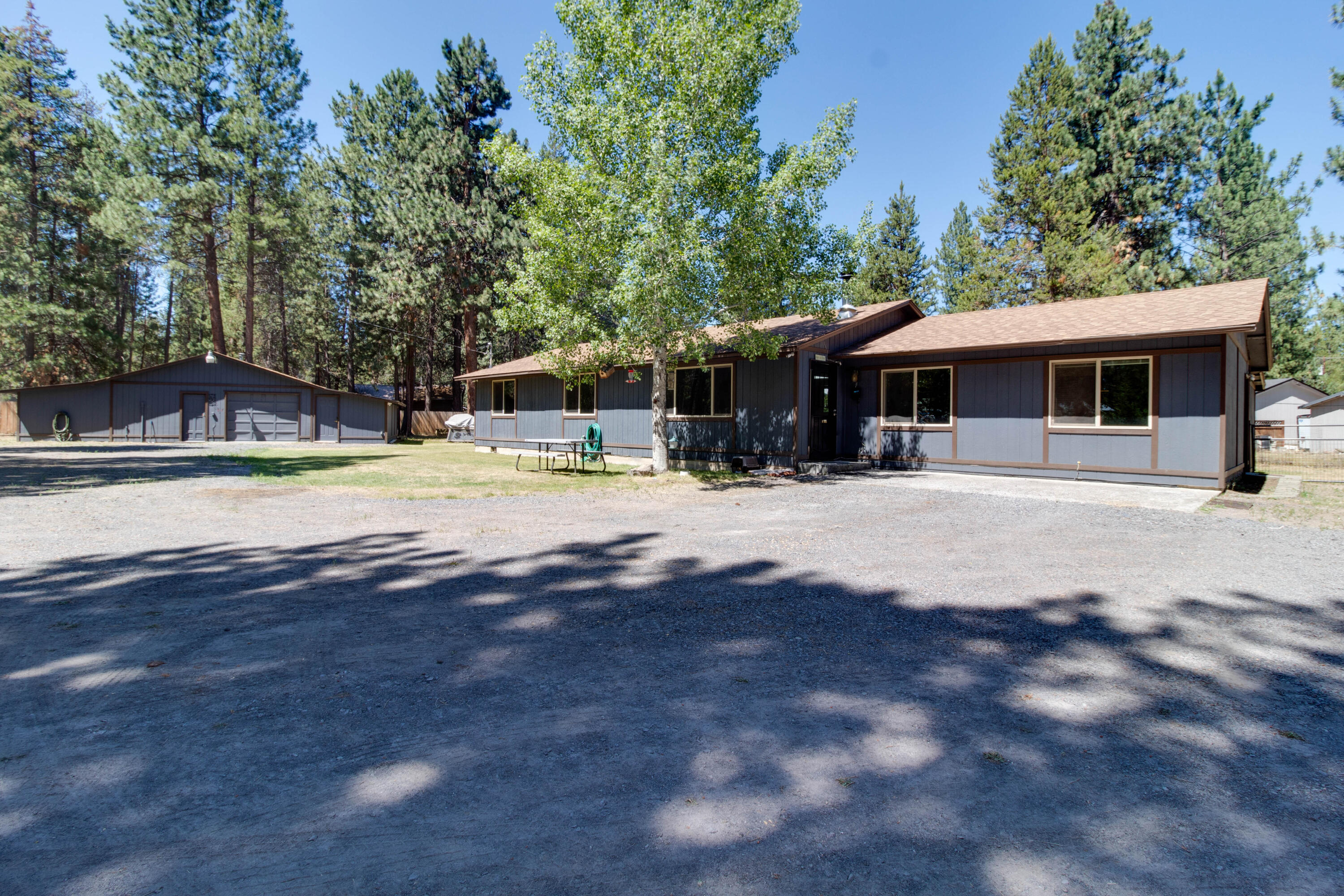Nicely located on fenced corner lot. Home has been well cared for with new roof and newly pumped septic.   Covered back deck with wood storage as well as storage for toys!  Attached garage was converted to a family room and extra bedroom, giving the home 4 spacious bedrooms. Laminate flooring throughout with carpeted bedrooms.  Living room has woodstove for those cold La Pine days and nights!  Interior home has been freshly painted.  Tile countertops in kitchen with ample cabinets.  Room for table off of Kitchen. Lots of storage throughout the home. Insulated attached Garage and workshop with woodstove, as well as two additions on sides of garage and workshop, both with electric.  Outdoor firepit with room for all your toys!!