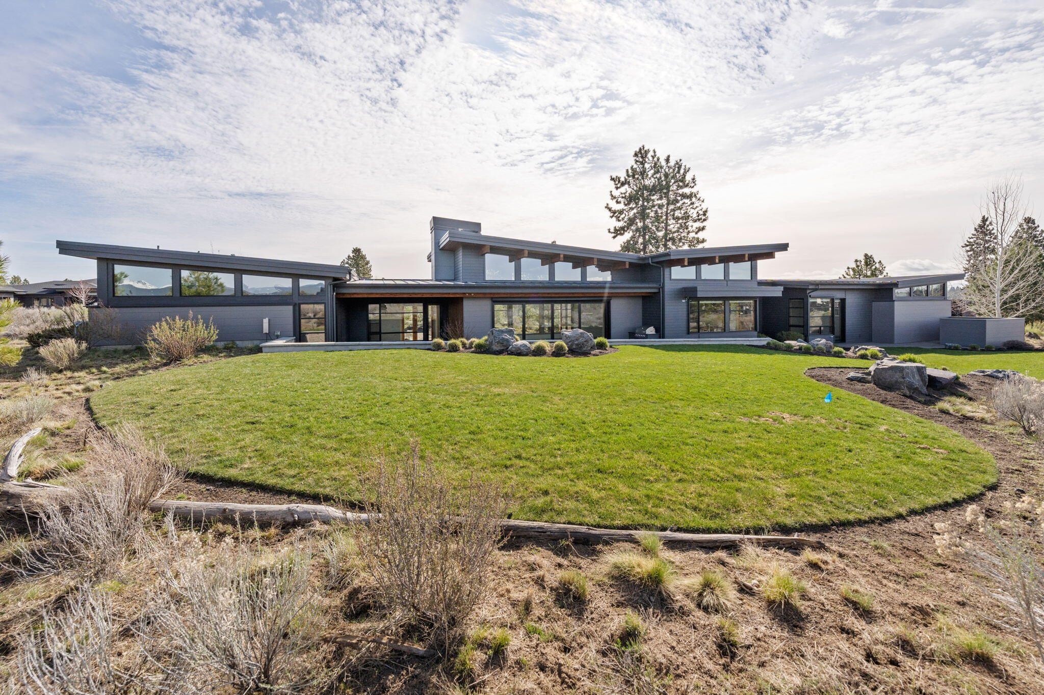 Unmatched quality meets elegant design in this Tetherow stunner! Enjoy breathtaking mountain views the moment you approach your front door. Situated on an expansive .90 acre lot, this thoughtfully designed single level gives separation between the primary suite and guest bedrooms located in opposite wings.Soaring ceilings in the great room and walls of windows to the east and west provide an abundance of light, controlled by self-adjusting interior shades and west side exterior sun shades to keep the house cool on hot summer days. In the south wing, a spacious primary bedroom with patio access, mud room, laundry room and office with to-die-for views. The north wing has two ensuite bedrooms and a bonus room, perfect for gym, theater or game room. The 3 car garage has a heated bay, epoxy floors and windows that make this feel like more than just a place to store the cars. All of this, located in the highly acclaimed Tetherow resort with golf, trails, pools & amenities just minutes away.