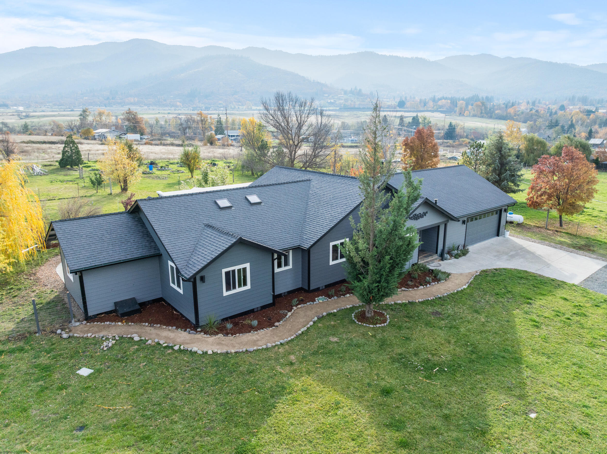 Stunning single-level contemporary home on 6.81 irrigated acres just minutes from downtown Ashland, Golf Course, & Emigrant Lake, yet privately tucked away at the end of Maywood Way among idyllic pasturelands. This custom home offers exceptional indoor-outdoor living. Light-filled spacious great room features vaulted Birdseye Pine ceiling, lime wash walls, hardwood floors, & elegant Tulikivi soapstone fireplace providing radiant warmth throughout. The open kitchen boasts granite countertops, center island, and gas range. Enjoy the large enclosed tiled patio with industrial screen, hot tub, and attached greenhouse room. Thoughtfully designed 4 bedrooms, 2 beautifully remodeled bathrooms with radiant floor heat & tiled showers. Ideal for farming, vineyard or equestrian pursuits with flat & fertile irrigated land, irrigation piping, water filtration & storage, garden, pastures, 1,728-sqft farm building, & 768-sqft flex space for art or office. Please do not drive by without appointment.