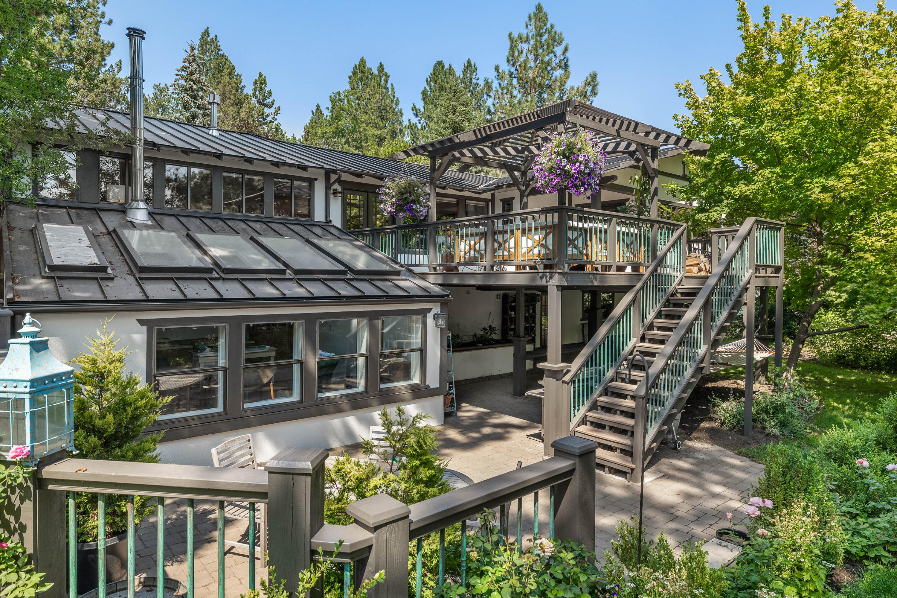 Mediterranean-inspired home blends old-world charm with contemporary design. Textured white walls are modernized with a new metal roof, bronze trim & beautiful patinaed copper accents creating an inviting atmosphere. The outside is brought in with abundant windows & numerous outside living areas. Get whisked away as you step into the gorgeous private courtyard and enter this elegant tree house.   Open concept kitchen, office nook, dining/living room, and primary suite are all located on the main floor with access to a large deck with pergola an entertainer's dream. On the lower level, you will find a full bath, laundry area, & 3 bdrms, 1 of which opens onto a paver patio.  There is an additional studio/flex room with its own outside exterior and interior entrance.  In the fenced backyard, you will be charmed by the private cottage garden with a sunken courtyard, raspberry patch, and heirloom fruit trees. A beautiful setting on a quiet tree-lined street with a park a block away.