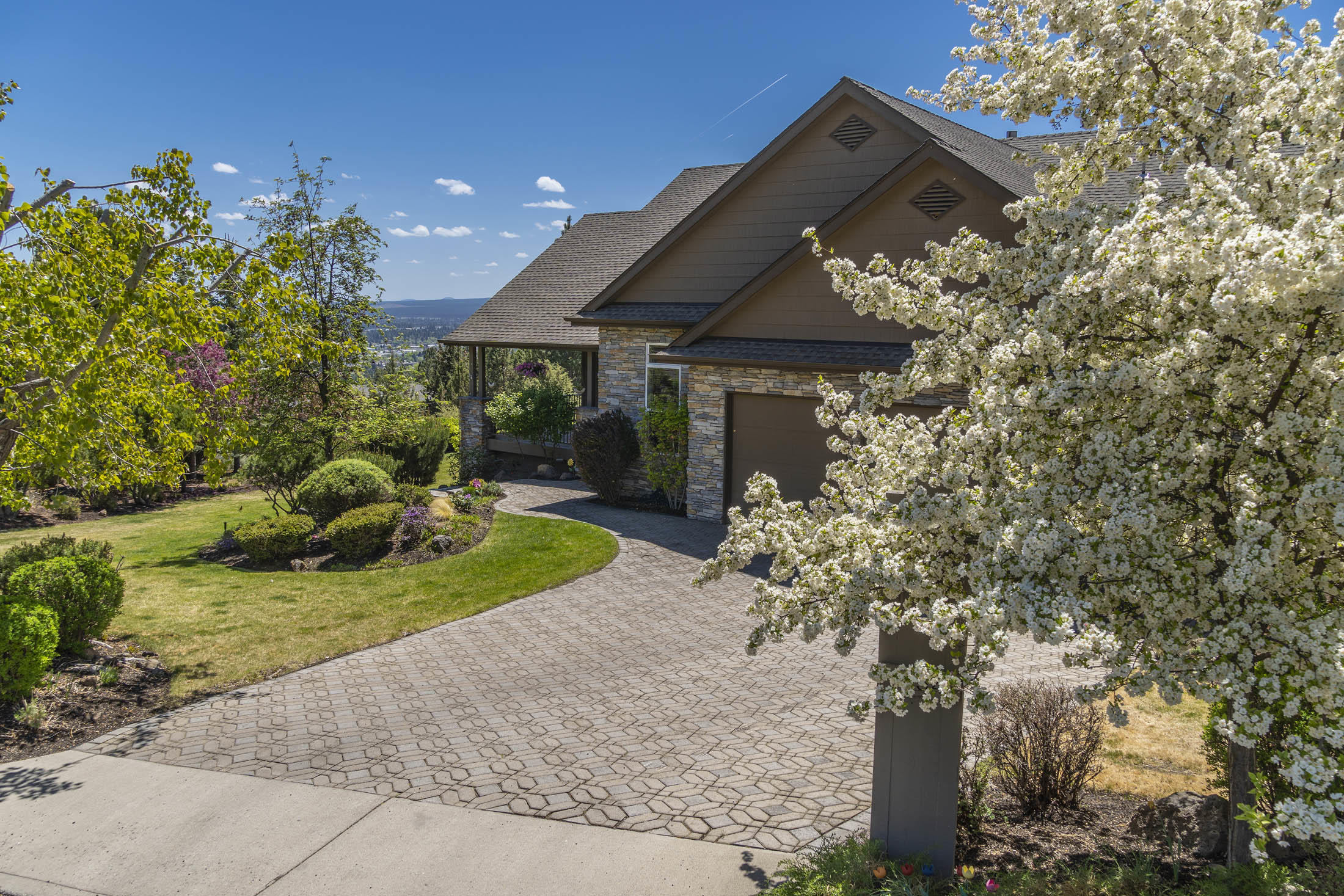 Peaceful and private setting on half an acre of beautifully landscaped level grounds. Expansive partial wrap around deck for entertaining and enjoying the city views & 4th of July fireworks! Optimum location just minutes to downtown with easy access to restaurants & shopping. Entering the front door you are greeted by soaring ceilings and large windows to capture the views. Cozy up by the fireplace in the great room. host a formal dinner party or keep it casual in the kitchen dining. Hickory cabinets, travertine backsplash and built in hutch to accompany the built in fridge and new dual fuel stove. Main level features primary bedroom with French doors to bathroom with jetted tub, dual vanity and large walk-in closet. Laundry with sink off of garage. Huge Bonus downstairs with private bedroom and bathroom. Easy to maintain paver driveway, exterior steps, lower patio. Oversized three car garage with workbench.