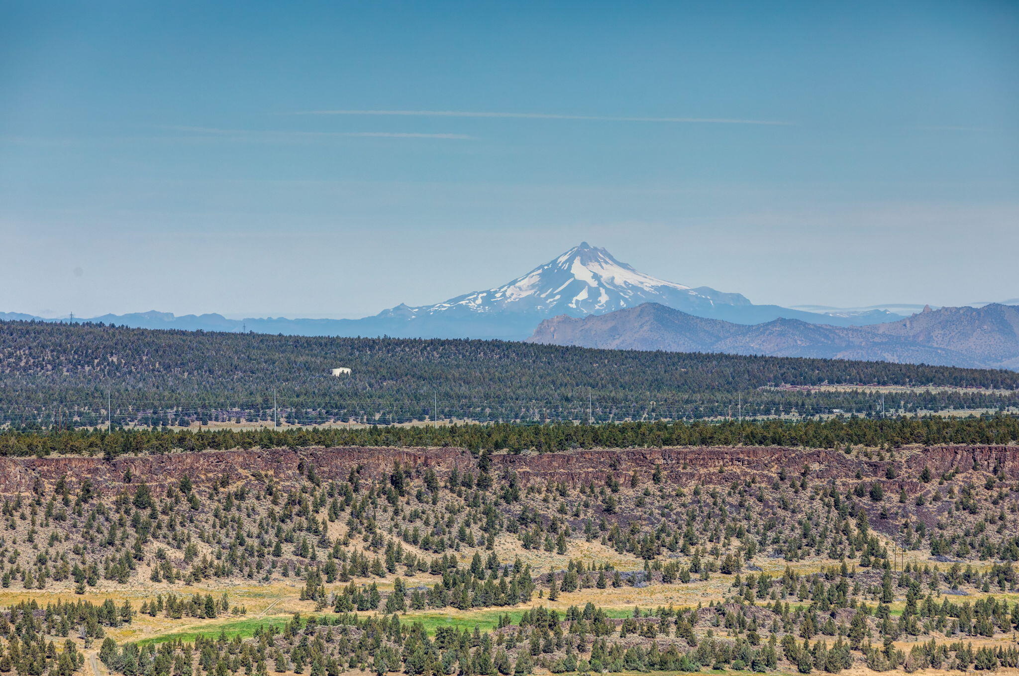Paramount in real estate is location & this unique property offers stunning, panoramic views of the Cascade Mtns & Crooked River Valley. Enjoy incredible vistas from the beautiful wrap-around deck, Great Rm, or Loft. This rare, well-maintained Log Home features distinctive burled accents & sculptures, vaulted wood ceilings, hickory floors, & solid pine doors. A must-see residence, it includes a spacious great rm, gourmet kitchen, laundry rm, two bedrms, & bathrm on the lower level while the upper level hosts a versatile flex space & primary bedrm w/ access to its own private deck & en-suite bathrm. Outside is a lovely water feature & detached log bunkhouse accommodating guests. For those passionate about shops, the property has a 720 SF heated garage w/ a workbench a & 1,440 SF RV shop, equipped w/ an RV dump & hookup nearby. Garden enthusiasts will appreciate the fenced raised flower beds w/ drip system. Embrace the beauty of living on the Canyon Rim where the world is yours to enjoy