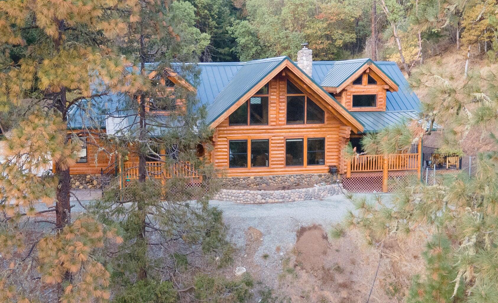 One-of a-kind Custom Cedar Log Home in the most desirable part of Canyonville, Oregon with stunning mountain and valley views. vaulted great room showcases soaring windows and a beautiful fireplace. Gourmet gas kitchen with natural edge granite, stainless appliances, and new cabinetry. Main-level primary and guest rooms offer easy living, while the spacious loft/game room with the spiral staircase adds endless possibilities. Brand-new paved driveway, cedar 3-car carport, and 32' x 48' fully insulated shop with 220 power and office provide exceptional function. Peaceful setting with city services and minimal upkeep. Just minutes from Seven Feathers Casino Resort, world class fishing, hunting, hiking, and golf. This home offers the best of Southern Oregon Living-luxury, and modern comfort in one property.  Room to easily add bedrooms off of deck or loft.