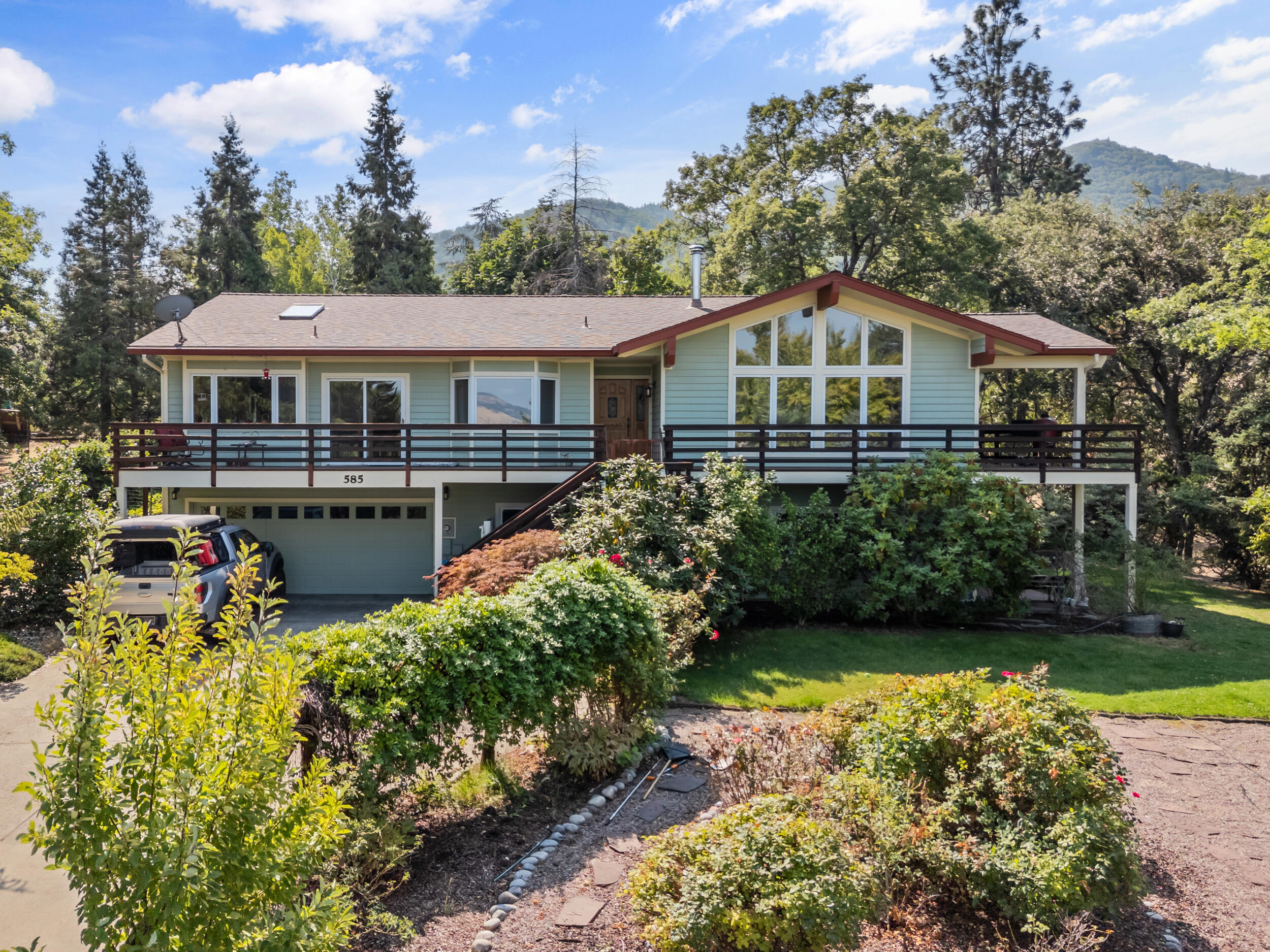This large 3,237 square foot home with panoramic views sits on a quiet cul-de-sac with a seasonal creek and an almost one-acre lot. Large windows and a wrap-around deck highlight the views, and there is a separate deck near the creek. Hiking trails begin only one block away. Open kitchen with custom mahogany cabinets, granite counter, Sub Zero Refrigerator overlooking Ashland. The kitchen, dining room and living room have an open floor-plan and recently refinished hardwood floors. Two of the bathrooms have custom tile-work. The lower level has a large bonus room, storage room, bathroom and another bedroom. There is an over-sized two-car garage with shelves and an abundance of storage space. Beautiful landscaping with lavender and rose gardens, a fountain, a greenhouse, extensive fencing. Very private and serene, yet you are only minutes to downtown.
