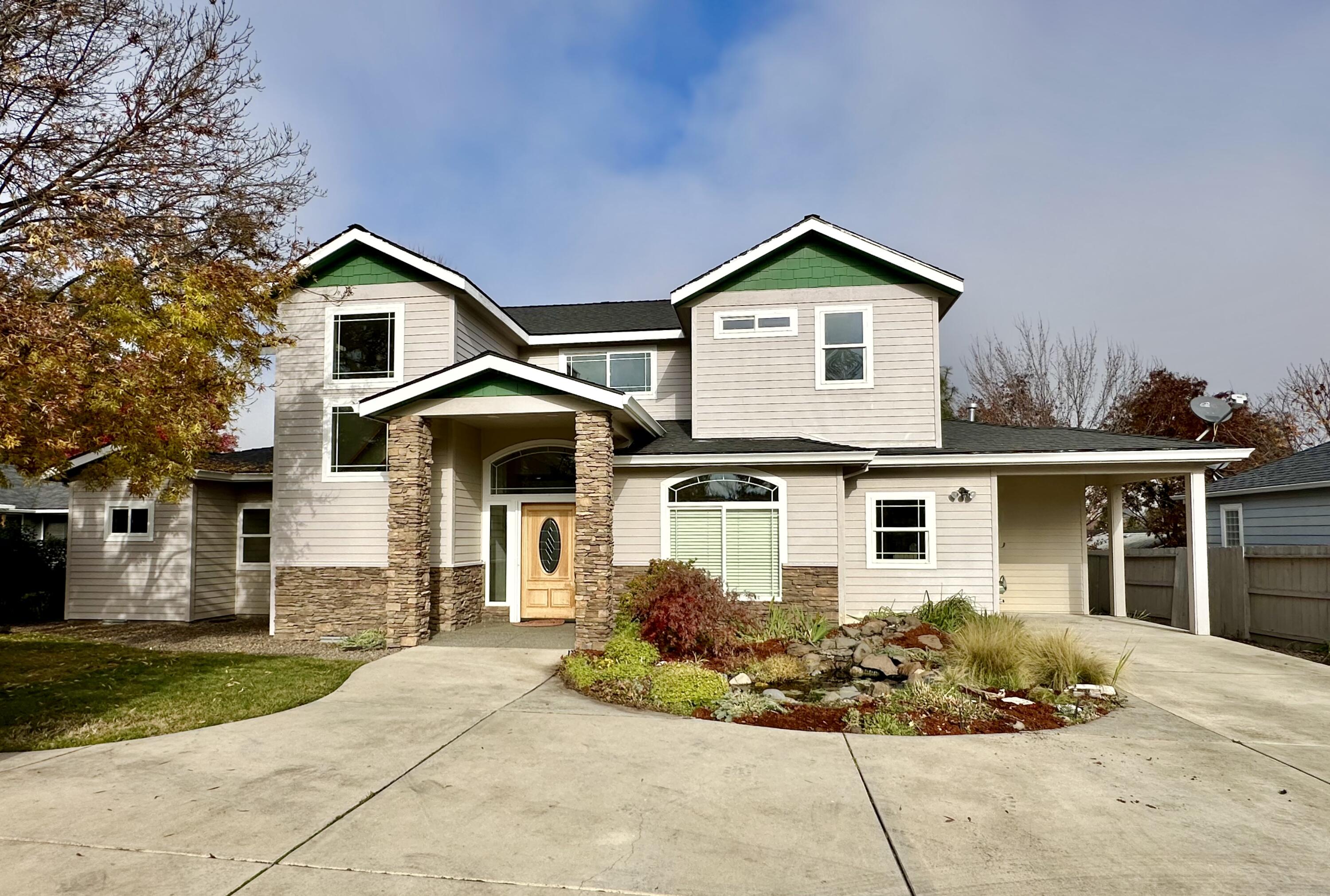 There is so much to love about this East Medford home including an over-sized 4-car detached garage with heated/cooled office/workshop, RV parking, mature landscaping with pond, fenced backyard, covered patios, main level primary bedroom suite, hardwood floors and so much more, all tucked away on a private flag drive. With 2,578 sf, 4 bedrooms and 3 bathrooms, this home welcomes you into the light-filled foyer and living room with soaring ceilings and large picture windows framing a gas fireplace. The spacious kitchen and dining area boasts granite countertops, breakfast bar, bay window and pantry. Enjoy lots of natural light in the primary suite with ensuite bathroom including tile floors, tiled shower and tile countertops with two sinks, plus a large walk-in closet and water closet. Upstairs you'll find two bedrooms, one with a walk-in closet, both with lovely neighborhood views, and a full bathroom. Lovely front and back yard spaces with manicured lawns. Excellent central location.