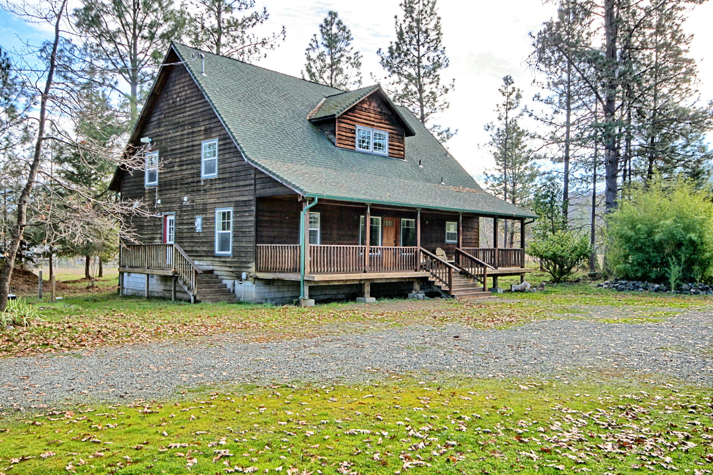 Modern Cedar Home on nearly 5 Acres with irrigation and good well! This 2240 sq.ft. cedar home blends charm, privacy, and potential. The level acreage offers fenced and cross-fenced gardens and pastures. Ideal for animals or hobby farming with multiple outbuildings including an equipment shed, storage/shop and a structure suited for small animals. Enjoy the peaceful country setting from the covered porch or yard with firepit. Inside, the open living area features vaulted ceilings and abundant natural light. The main level includes a spacious primary suite with walk-in closet and jetted tub, plus a guest room and full bath. Upstairs offers another bedroom, full bath, large storage closet, and an almost finished bonus room above the laundry perfect for an office or craft space. Trees around the home provide shade and enhance the sense of privacy.